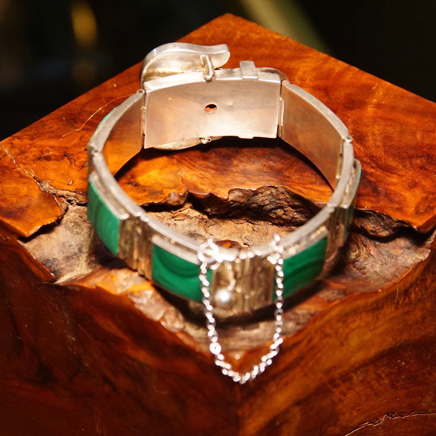 Antique Victorian silver bracelet with malachite inlay, ornate etched designs, and buckle-style links, measuring 7 1/8 inches long, displayed on rustic wooden surface.