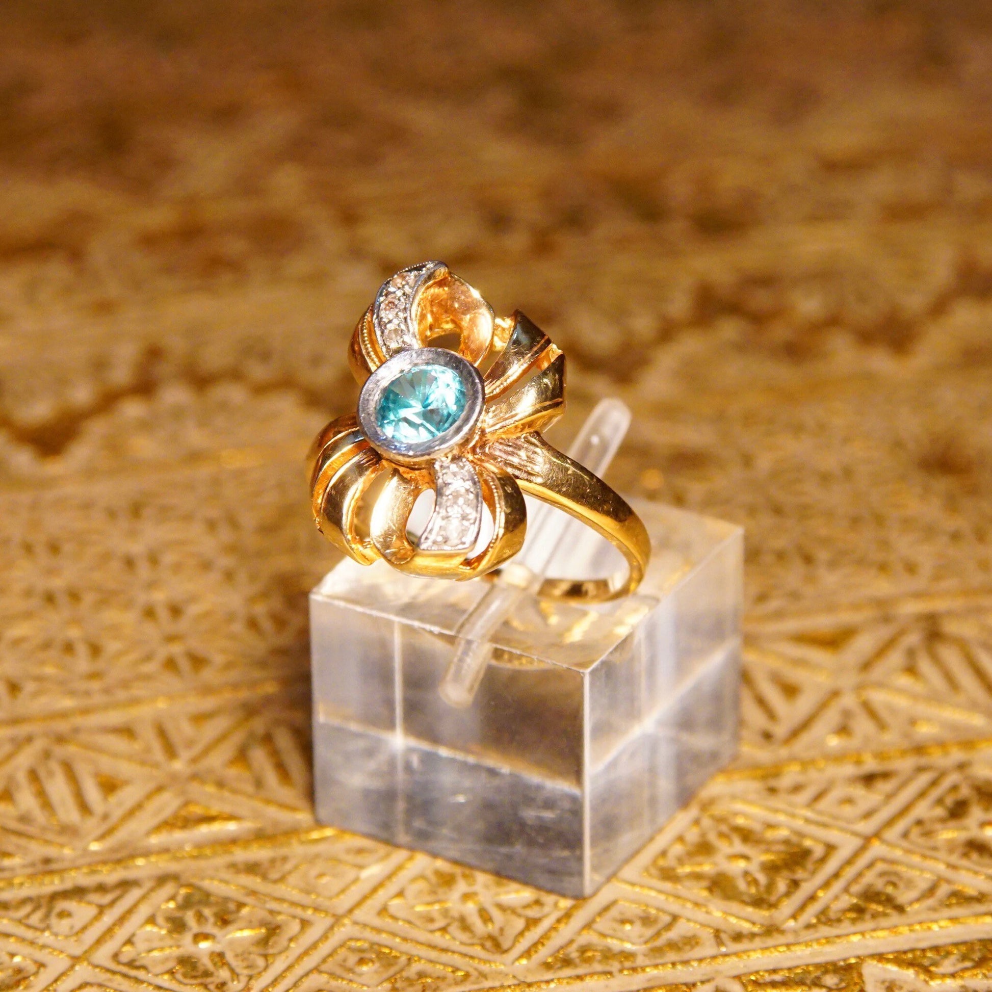 Antique 10K gold blue topaz and diamond ribbon bow ring featuring a brilliant blue gemstone in a ribbon setting with white gold accents, made by JR Woods & Sons, size 6 3/4 US.