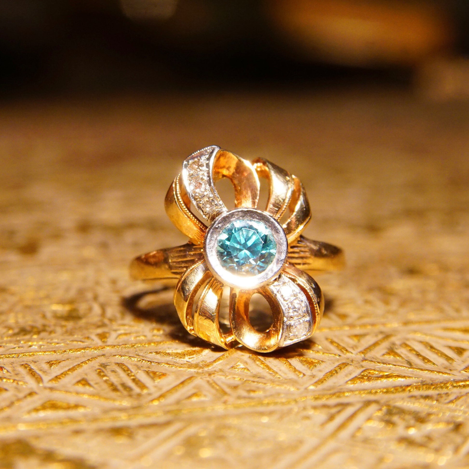 Antique 10K gold blue topaz and diamond bow ring featuring a brilliant blue gemstone in a ribbon setting with white gold accents, made by JR Woods & Sons, size 6 3/4 US.