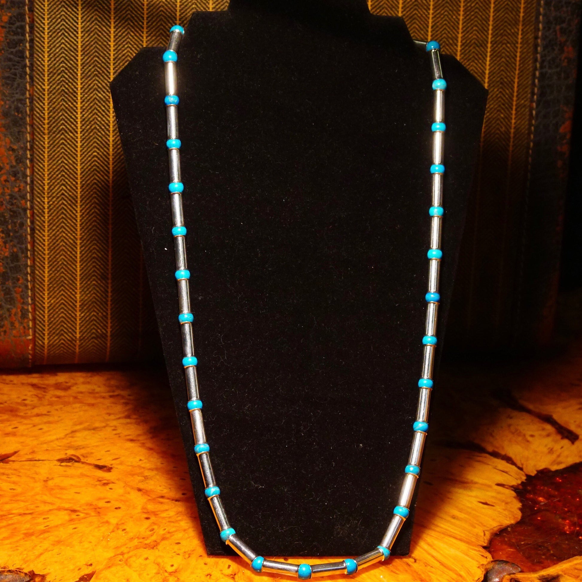 Vintage Navajo sterling silver tube bead necklace with turquoise spacer beads and pearls, measuring 32 1/2 inches long, displayed on textured brown fabric background.