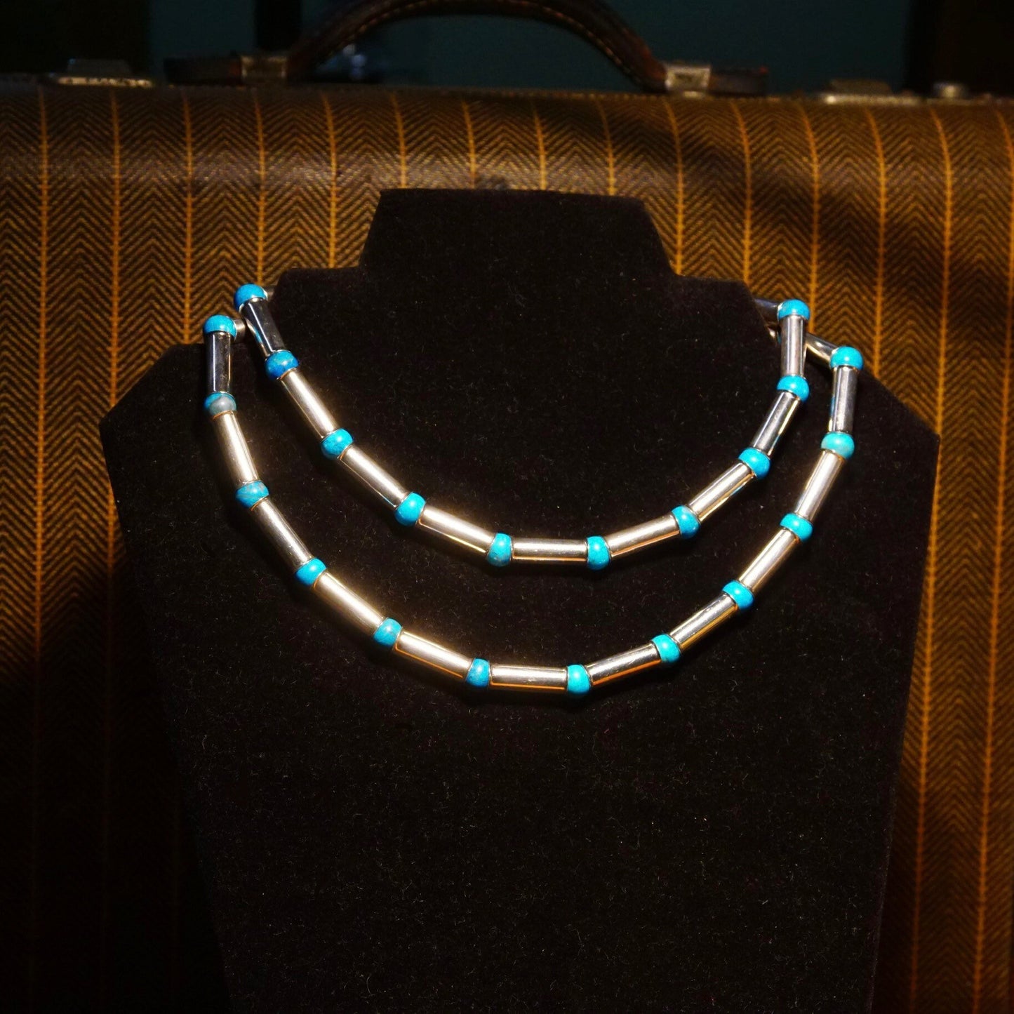 Vintage Navajo sterling silver and turquoise necklace featuring tube beads, blue turquoise spacers, and pearl bench barrel beads, measuring 32 1/2 inches long, displayed on dark fabric background.