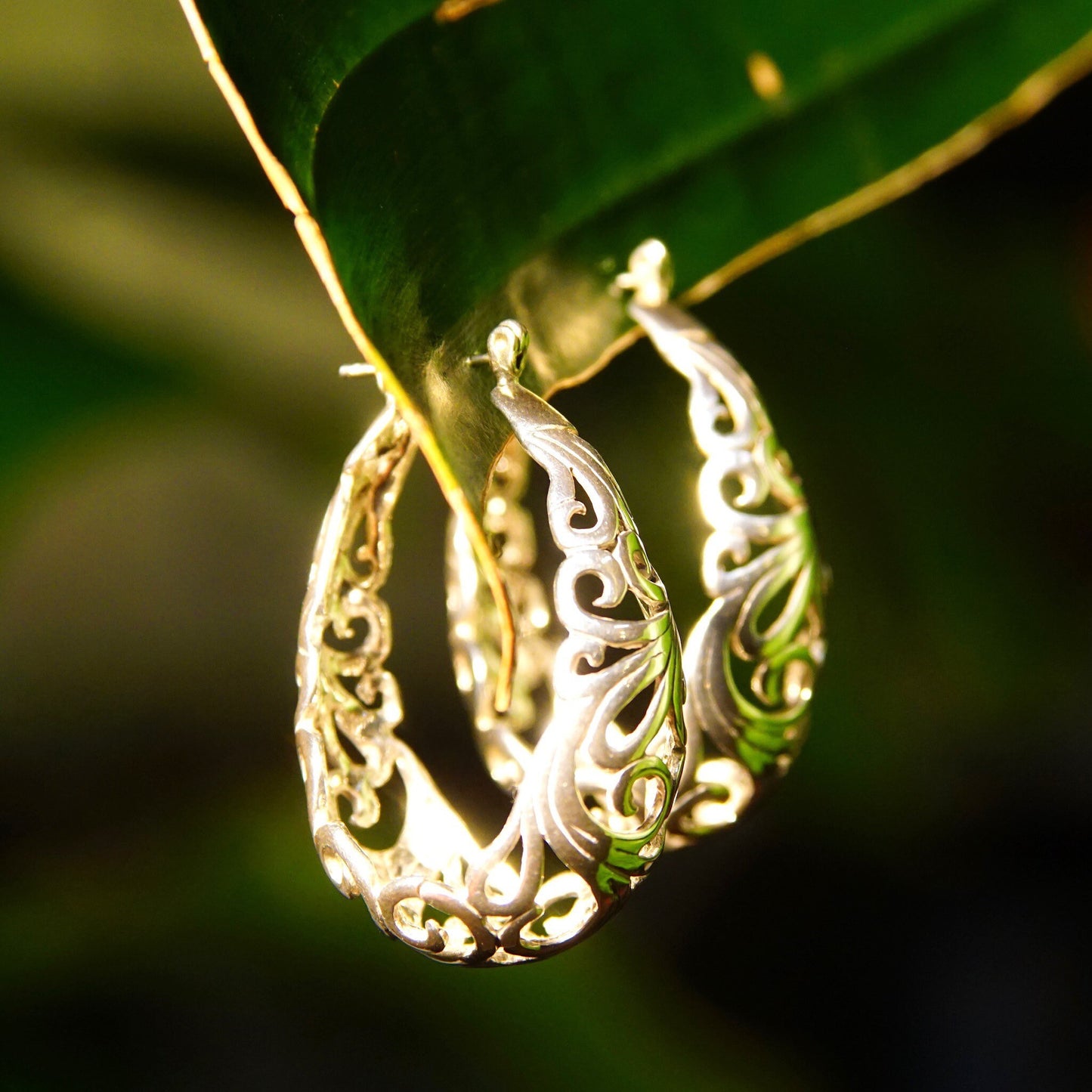 Vintage sterling silver filigree oval hoop earrings with intricate Art Nouveau vine and scroll designs, measuring 1 3/8 inches in length.