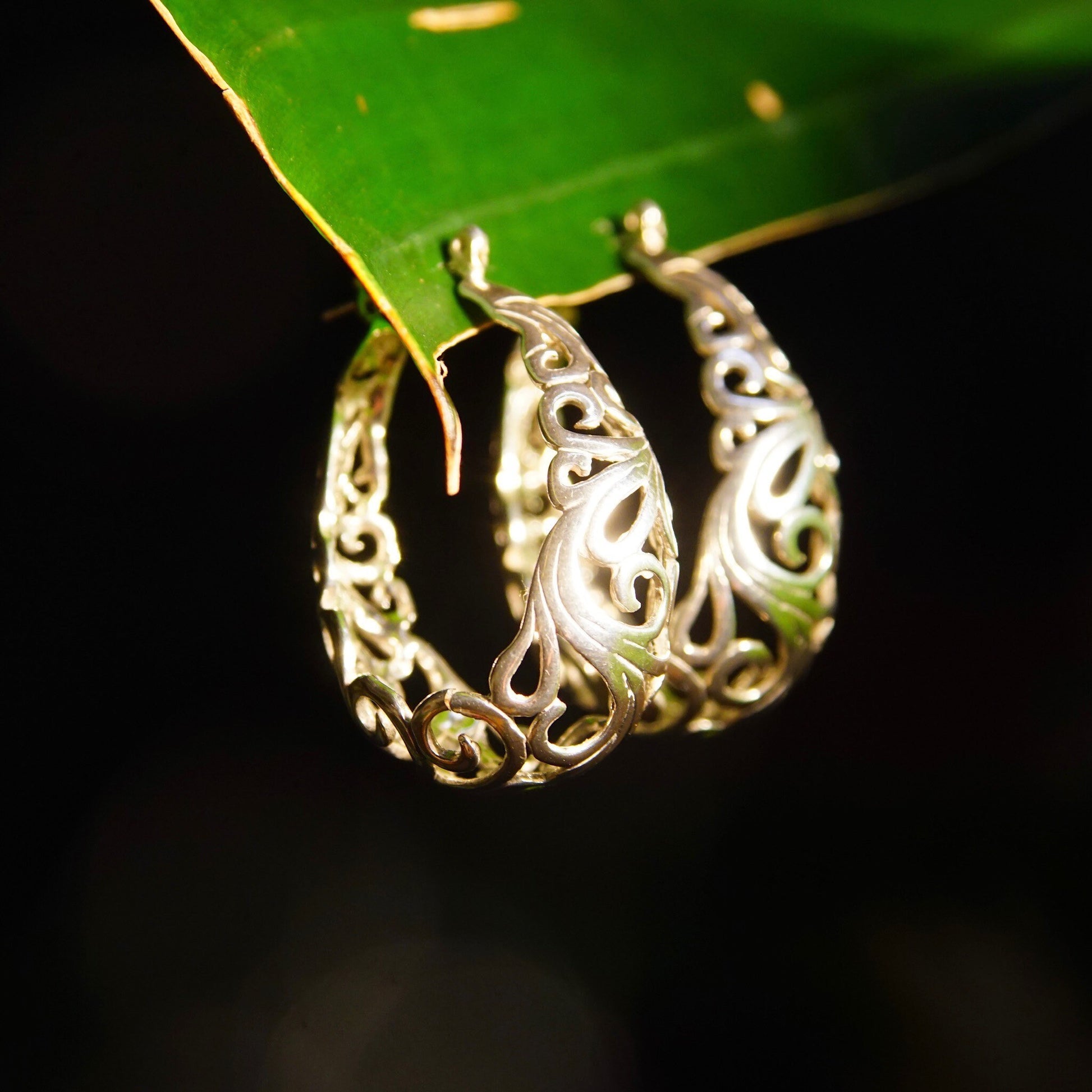 Vintage sterling silver filigree oval hoop earrings with intricate art nouveau vine and scroll designs, measuring 1 3/8 inches long.