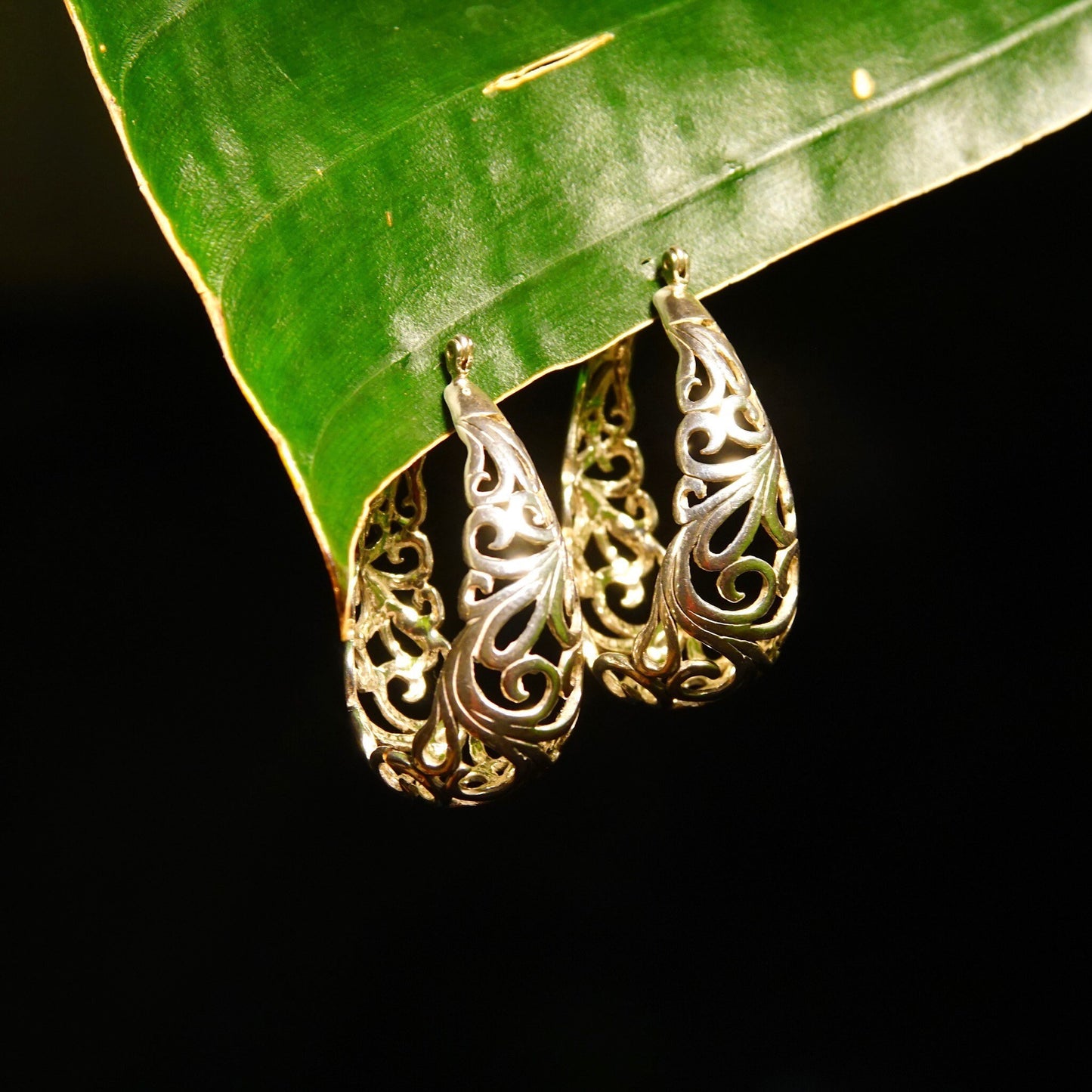 Vintage sterling silver filigree oval hoop earrings with intricate Art Nouveau vine and scroll designs, measuring approximately 1 3/8 inches in length.