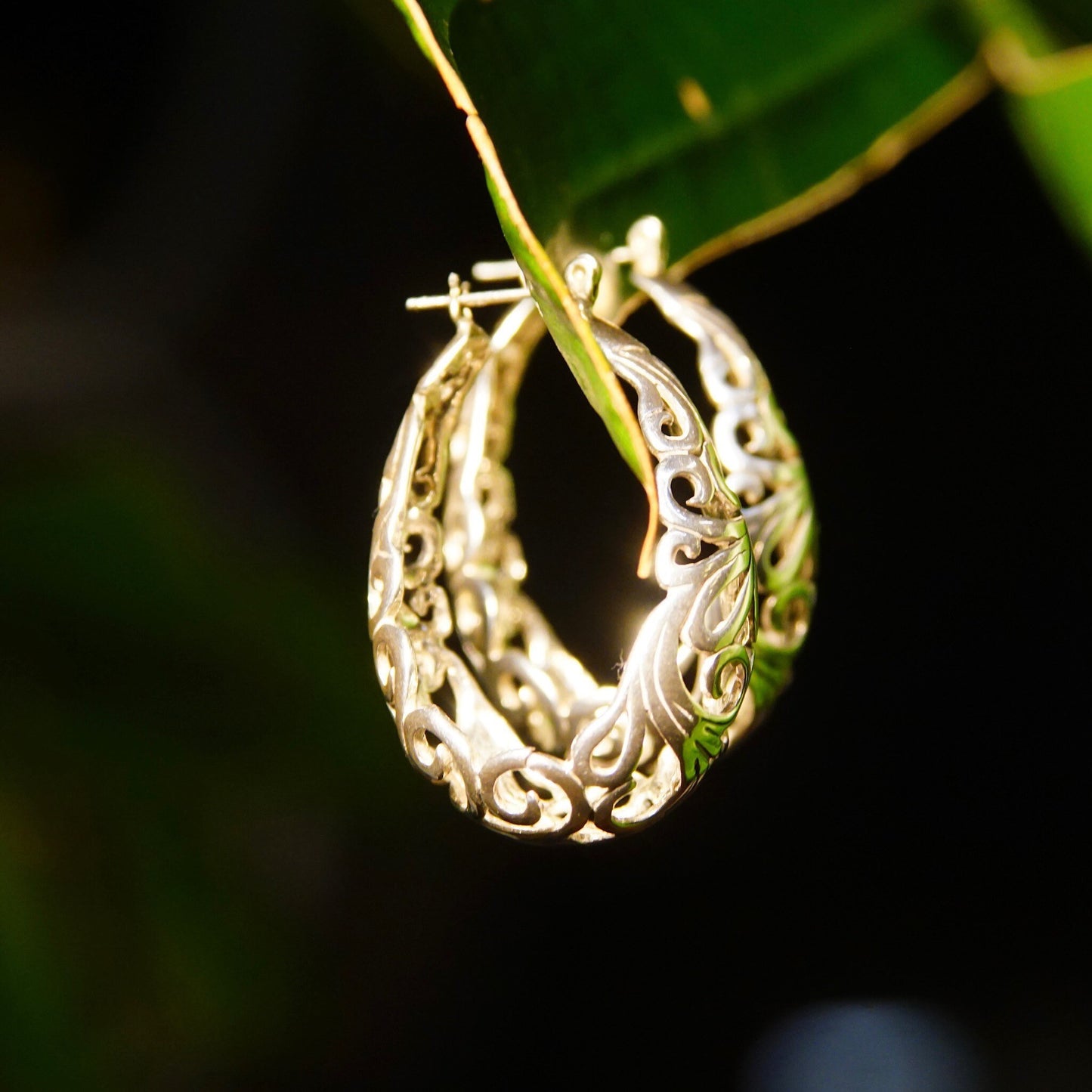 Vintage sterling silver filigree oval hoop earrings with pierced basket design featuring art nouveau vine and scroll motifs, measuring 1 3/8 inches long.