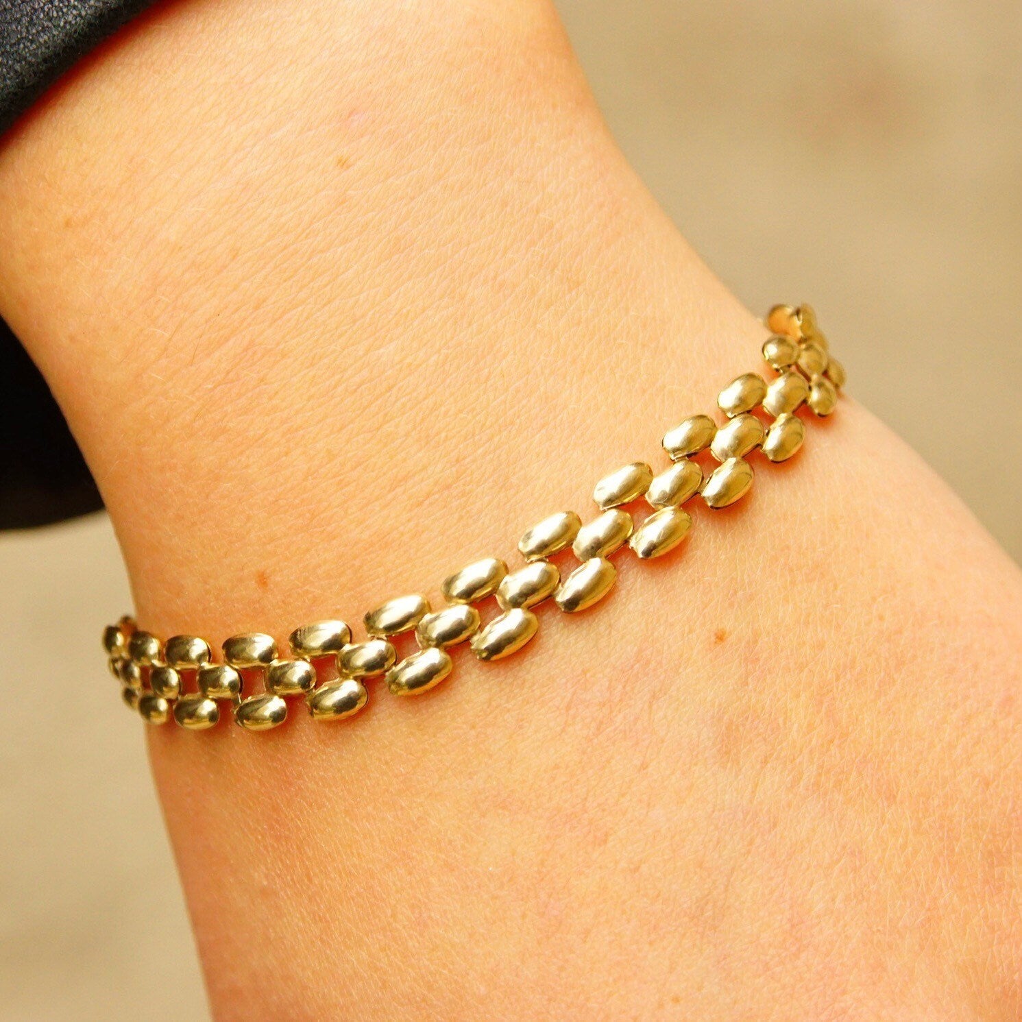 Vintage 10K gold panther link chain bracelet with puffed yellow gold multi-row links, measuring 8mm wide and 7 1/2 inches long, resting on a person's wrist.