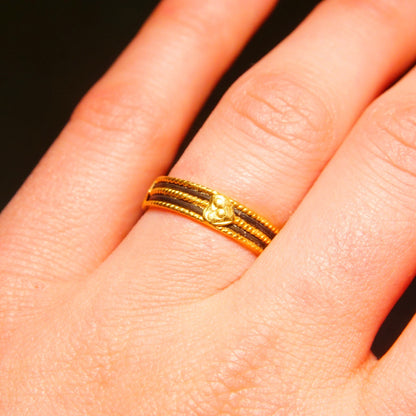 Vintage 22K yellow gold wedding band with black enamel inlay and gold heart embellishments on a woman's finger, handmade Indian jewelry.