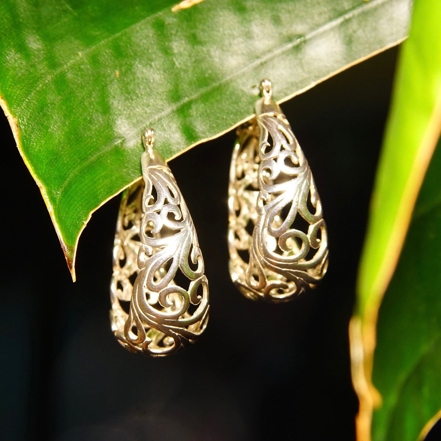 Vintage sterling silver filigree oval hoop earrings with intricate Art Nouveau vine and scroll designs, measuring 1 3/8 inches long.