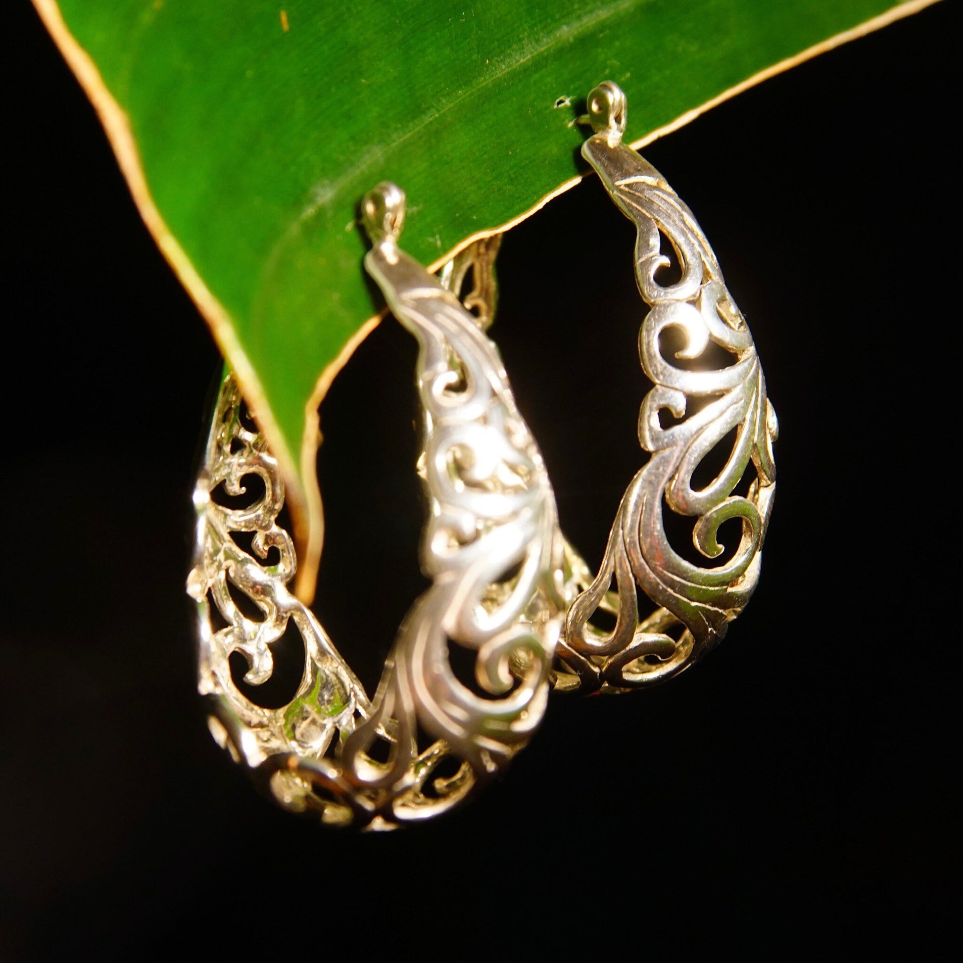 Vintage sterling silver filigree oval hoop earrings with intricate art nouveau vine and scroll designs, measuring 1 3/8 inches long.