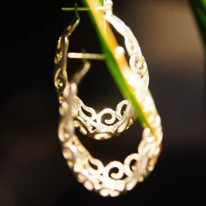 Vintage sterling silver filigree oval hoop earrings with intricate art nouveau vine and scroll designs, measuring 1 3/8 inches long.