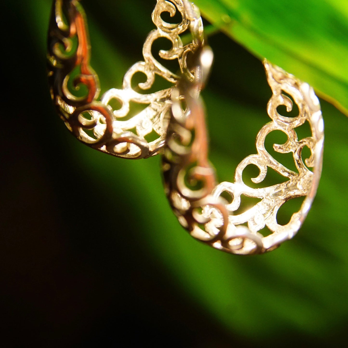 Vintage sterling silver filigree oval hoop earrings with intricate art nouveau vine and scroll designs, measuring 1 3/8 inches long.