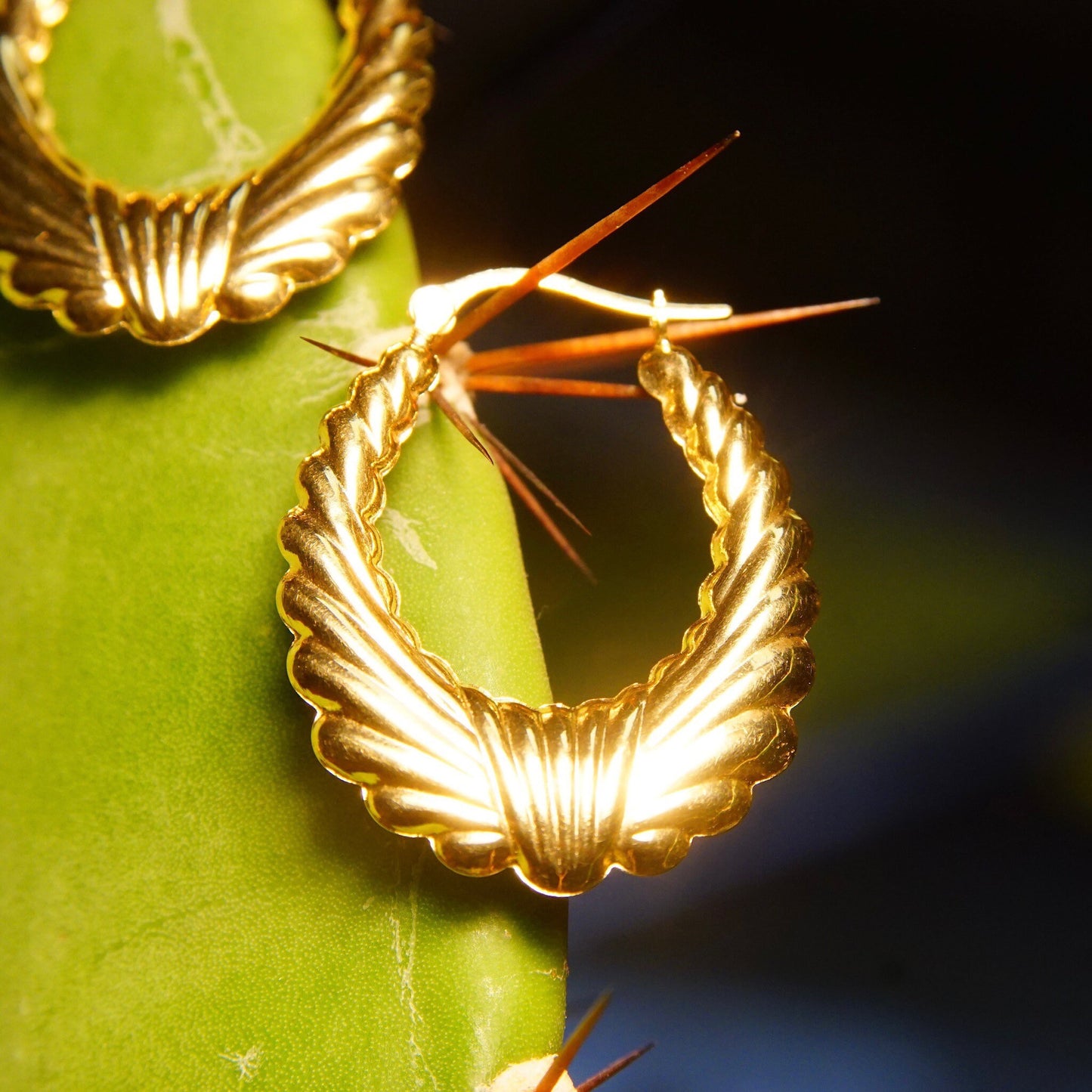 Vintage 14K yellow gold scalloped hoop earrings in a puffed wreath design, measuring approximately 1 1/4 inches long, showcasing the detailed texture and sophisticated style of the 585 gold against a green background.