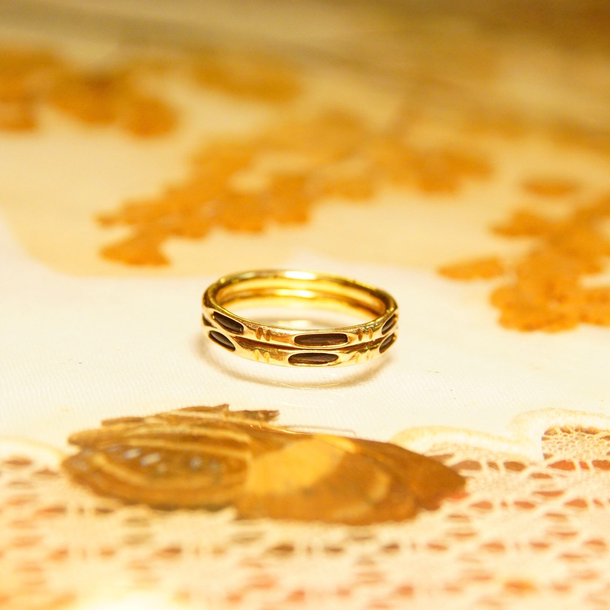 14K gold bamboo-style stacking rings with black strand accents on lace tablecloth