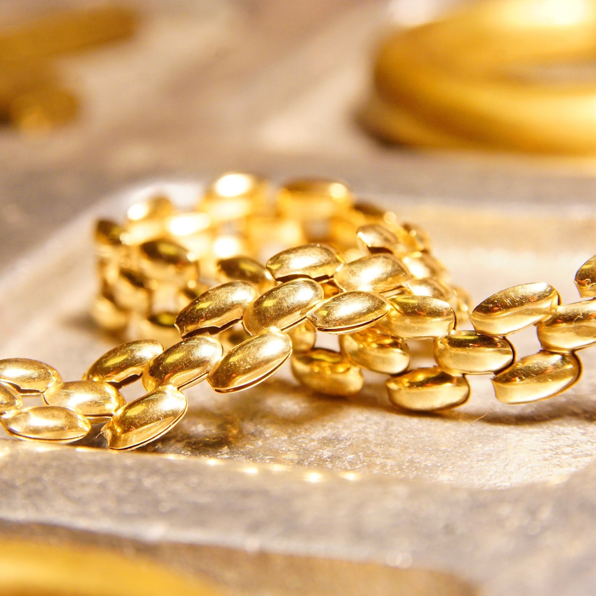 Vintage 10K gold panther link chain bracelet with 8mm multi-row puffed yellow gold links, measuring 7 1/2 inches long, displayed on a textured beige surface.