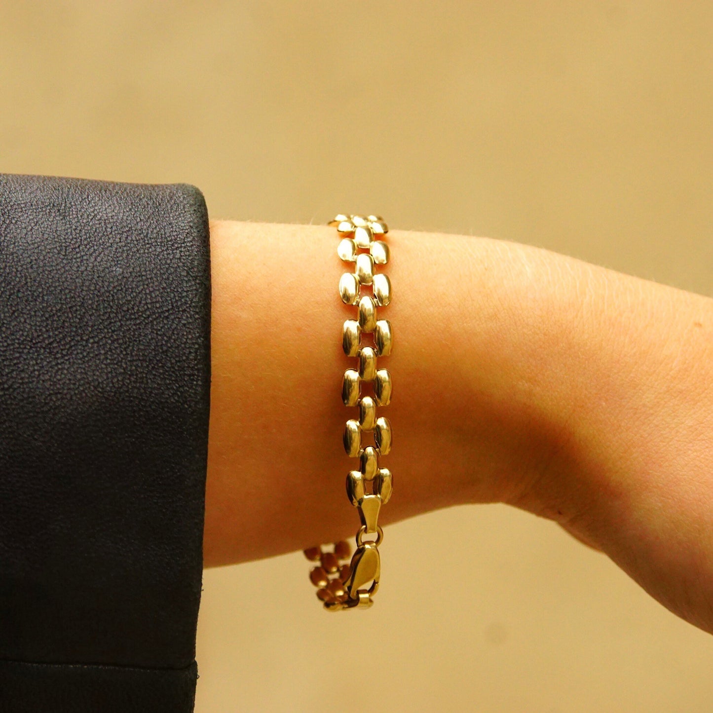 Vintage 10K yellow gold panther link chain bracelet with 8mm multi-row puffed links, measuring 7 1/2 inches long, shown on a person's wrist against a tan background.