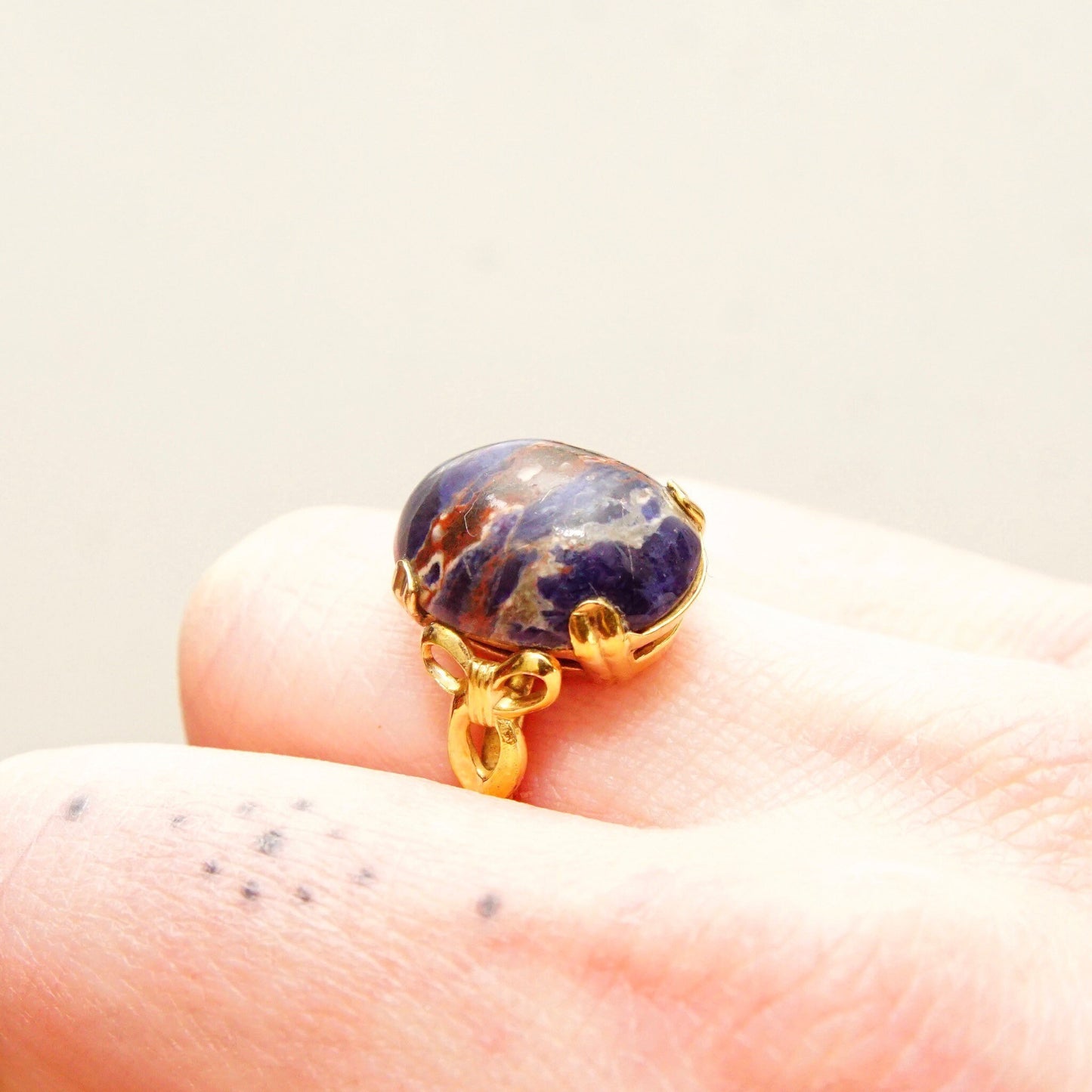 Vintage 10K gold-filled lapis lazuli cabochon ring featuring a dark blue gemstone with natural inclusions, accented by yellow gold ribbon embellishments, in a size 8 US.