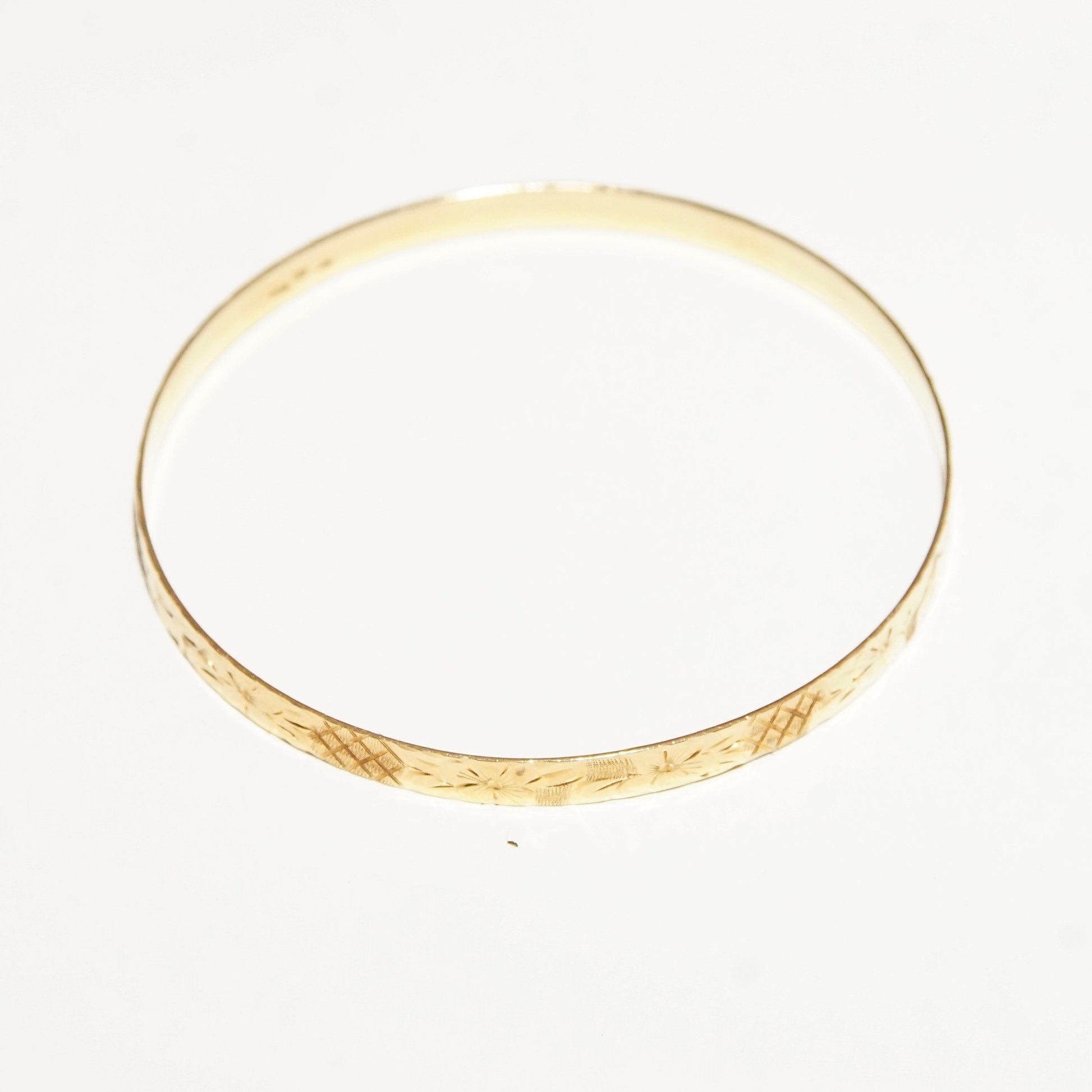 14K yellow gold bangle bracelet with diamond-cut floral designs, 5mm wide, perfect for stacking or wearing alone.