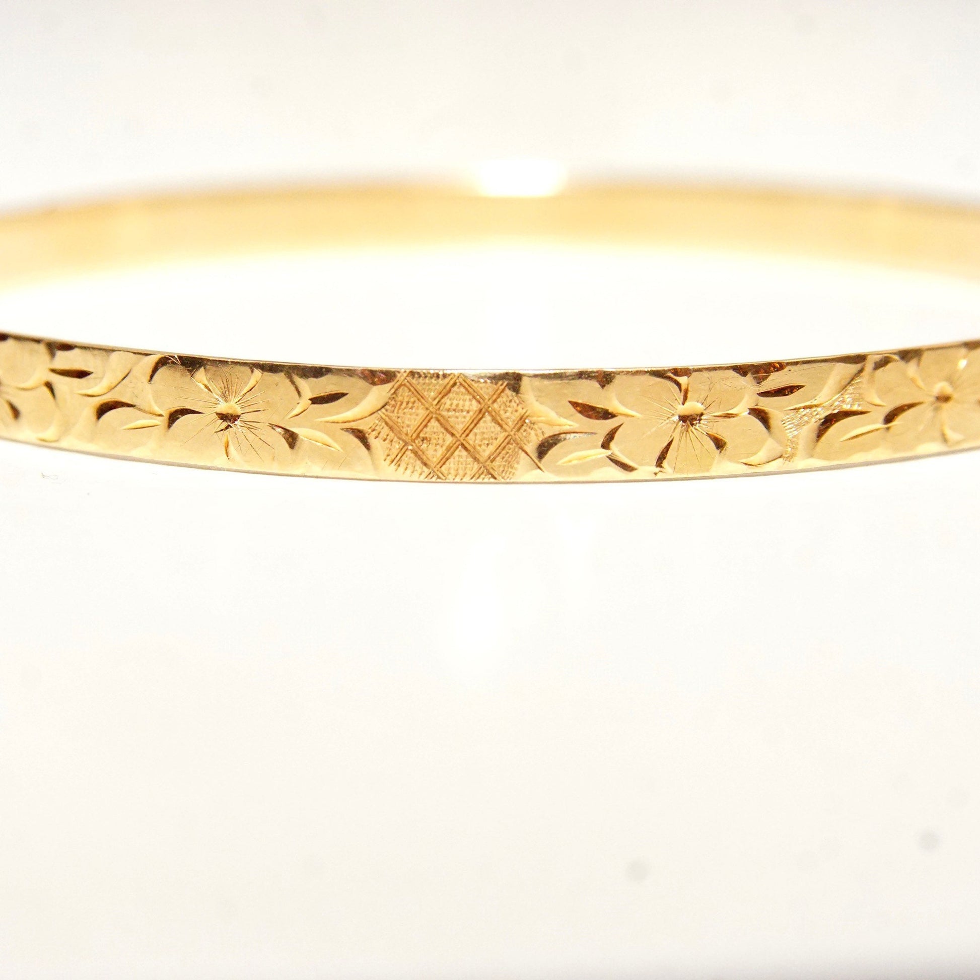 14K yellow gold bangle bracelet featuring intricate diamond-cut floral and leaf motifs, 5mm wide, perfect for stacking or wearing solo.