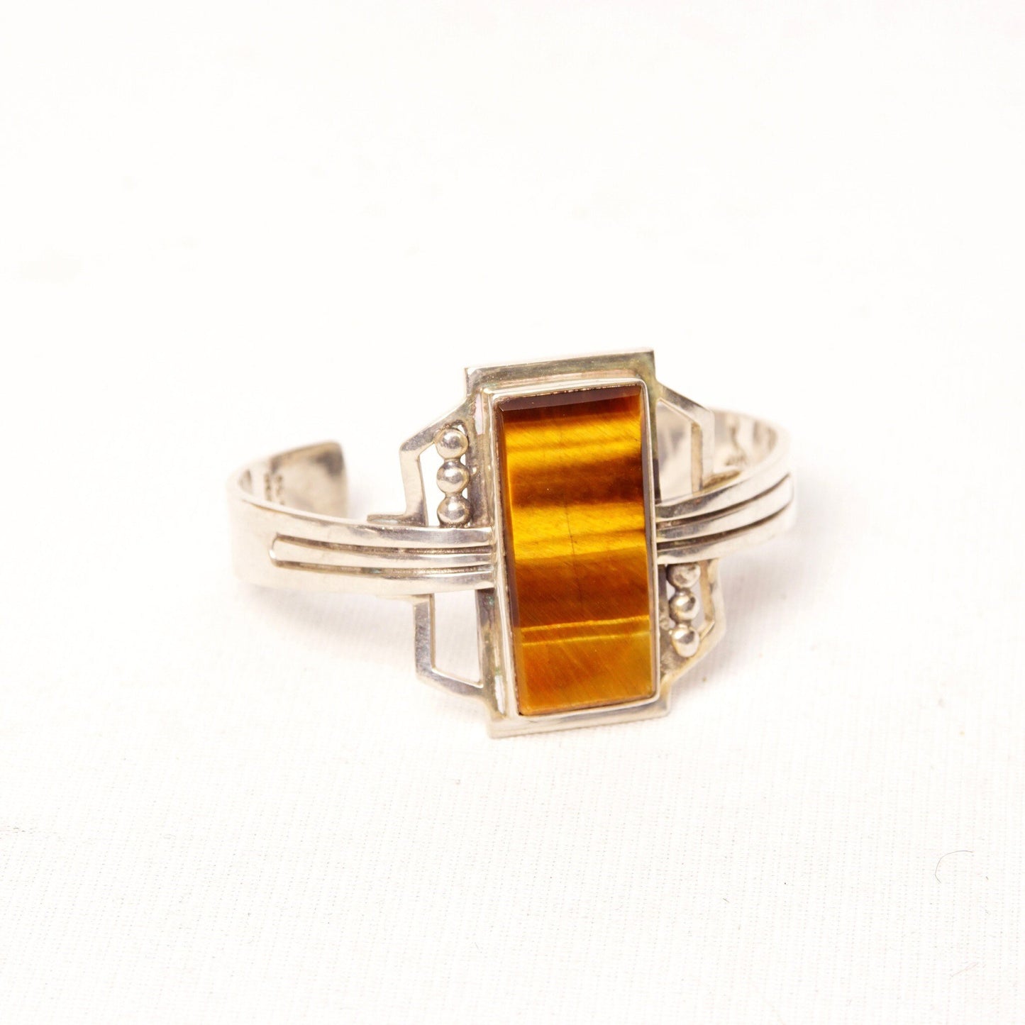 Vintage Taxco sterling silver cuff bracelet featuring a polished rectangular tiger's eye gemstone, with engraved "Mexico 925" hallmark, measuring 5 1/8 inches long.