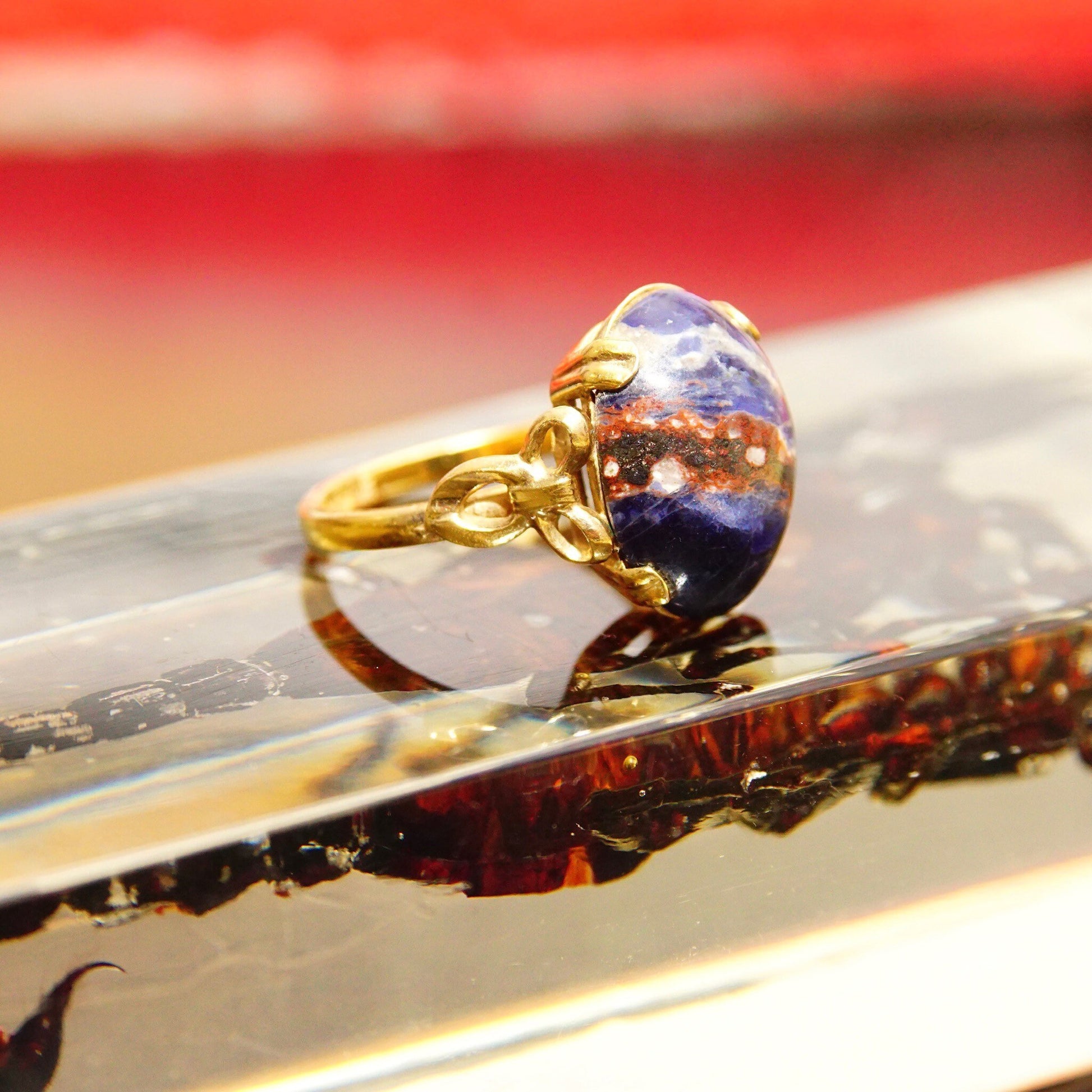 Vintage 10K gold-filled ring featuring a dark blue lapis lazuli cabochon gemstone with inclusions, adorned with decorative yellow gold ribbon detailing, size 8 US.