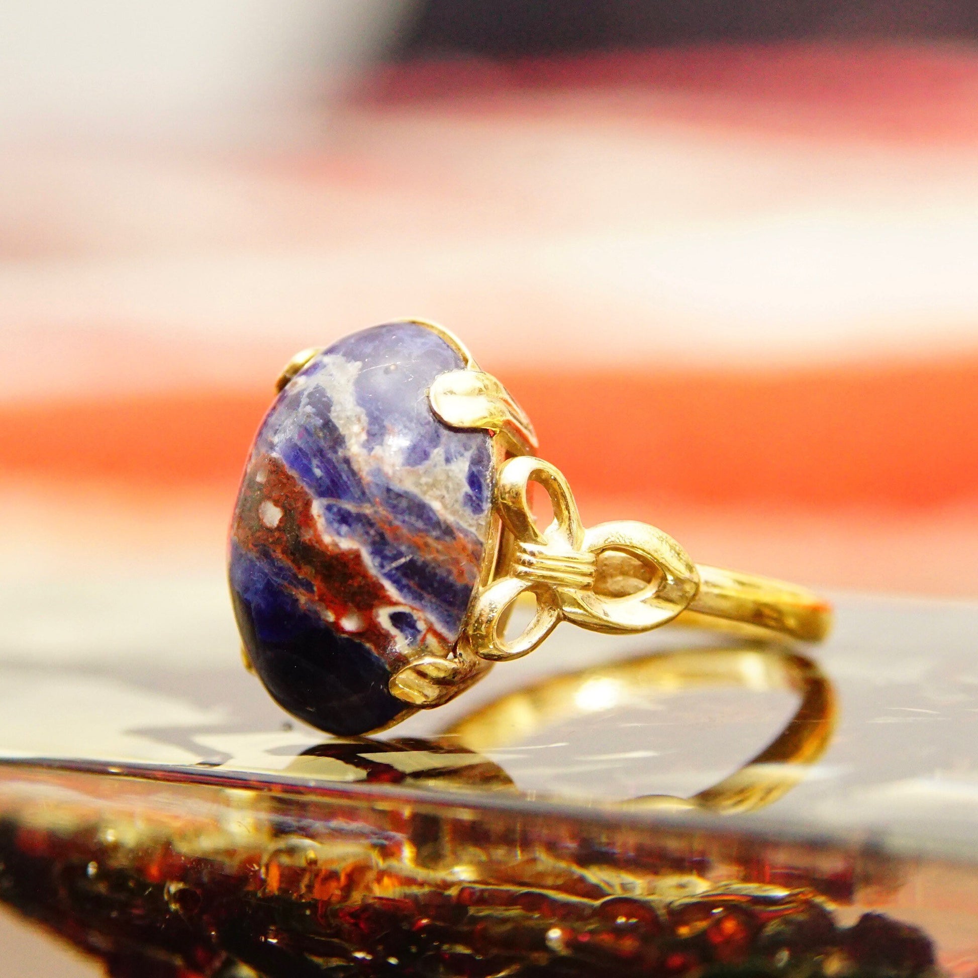 Vintage 10K yellow gold lapis lazuli cabochon ring with dark blue gemstone showing pyrite inclusions, ribbon embellishments on the band, size 8 US.