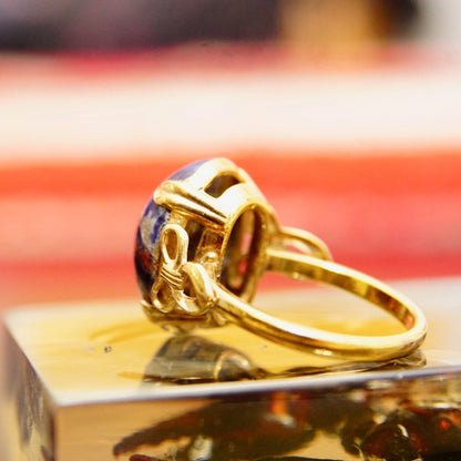 Vintage 10K yellow gold filled ring featuring a round dark blue lapis lazuli cabochon with golden pyrite inclusions, ribbon motif embellishments on the mounting, size 8 US.