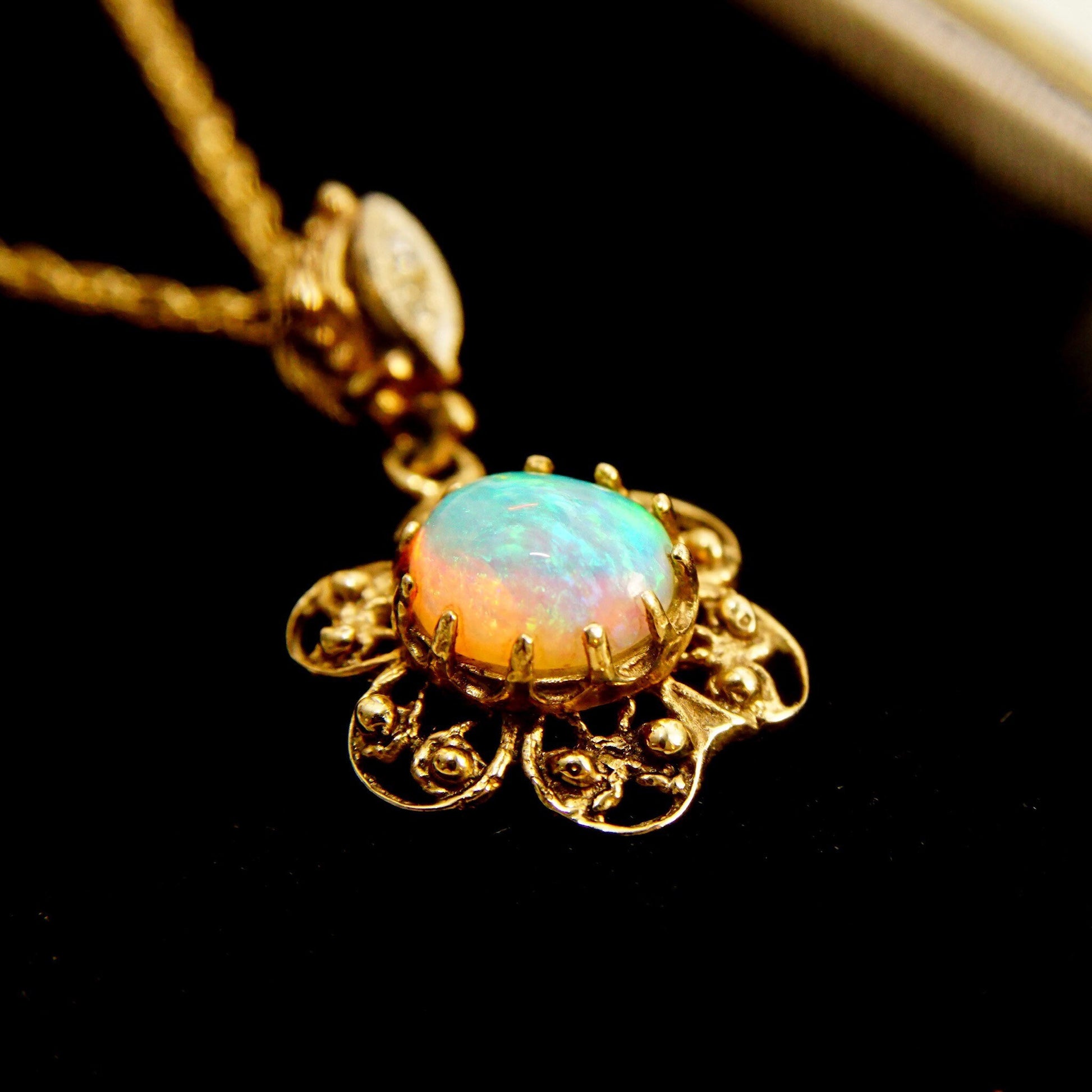 14K gold filigree necklace featuring an opal cabochon pendant in a flower design with two diamond accents, suspended from a delicate 1.5mm rope chain measuring 21 inches in length.