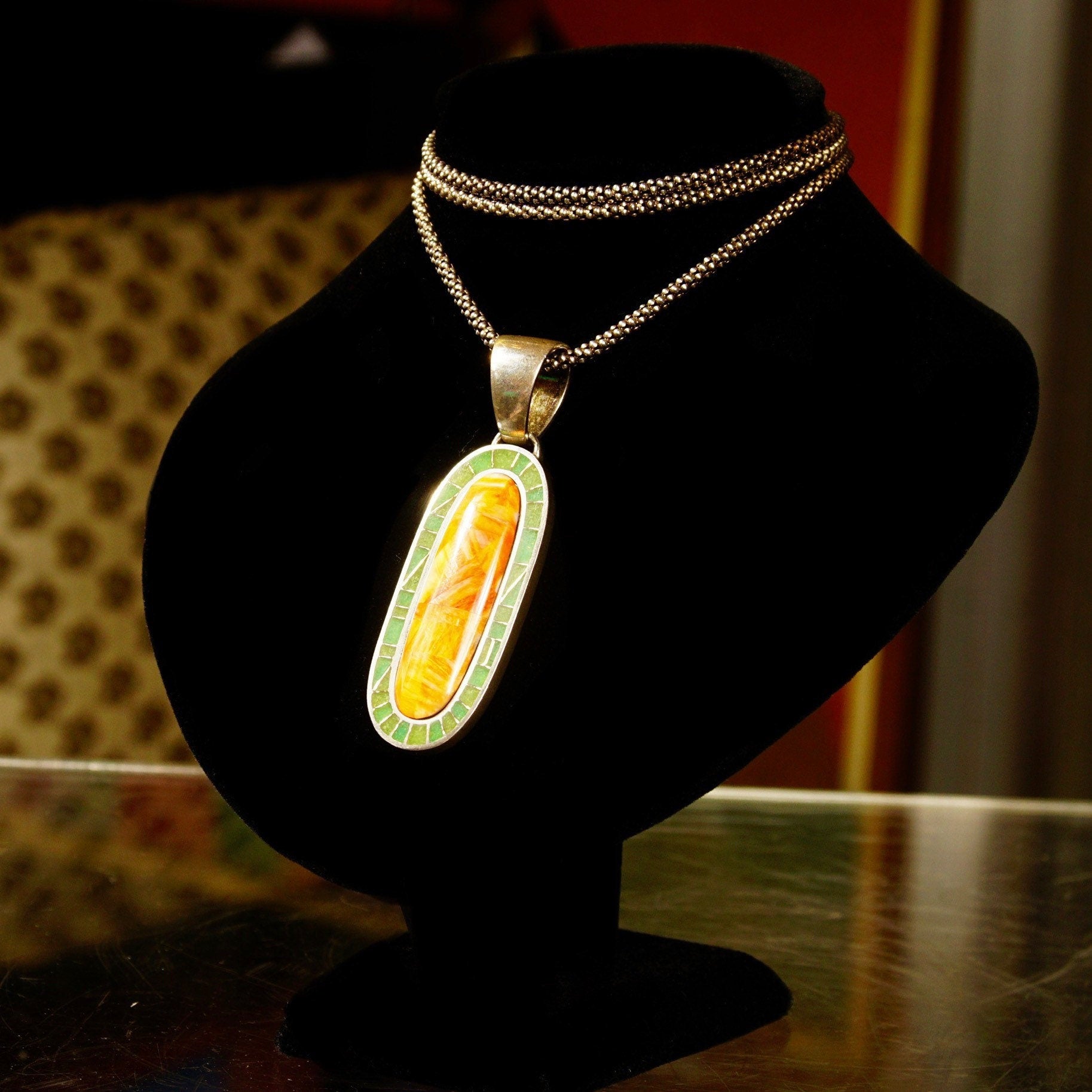 Vintage 925 sterling silver mosaic pendant necklace with orange carnelian agate and green aventurine inlay on a black velvet bust display stand.