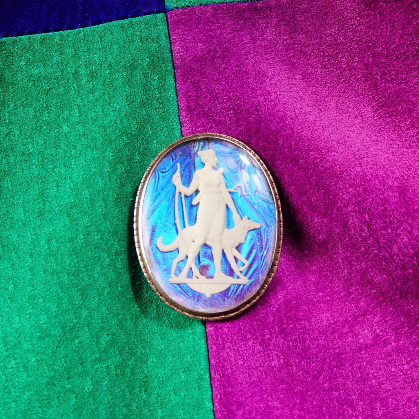 Vintage Art Deco sterling silver butterfly wing cameo brooch featuring iridescent sulfide cameo depicting Grecian goddess, made in England, measuring 1 3/4 inches long, set against green and pink textured background.