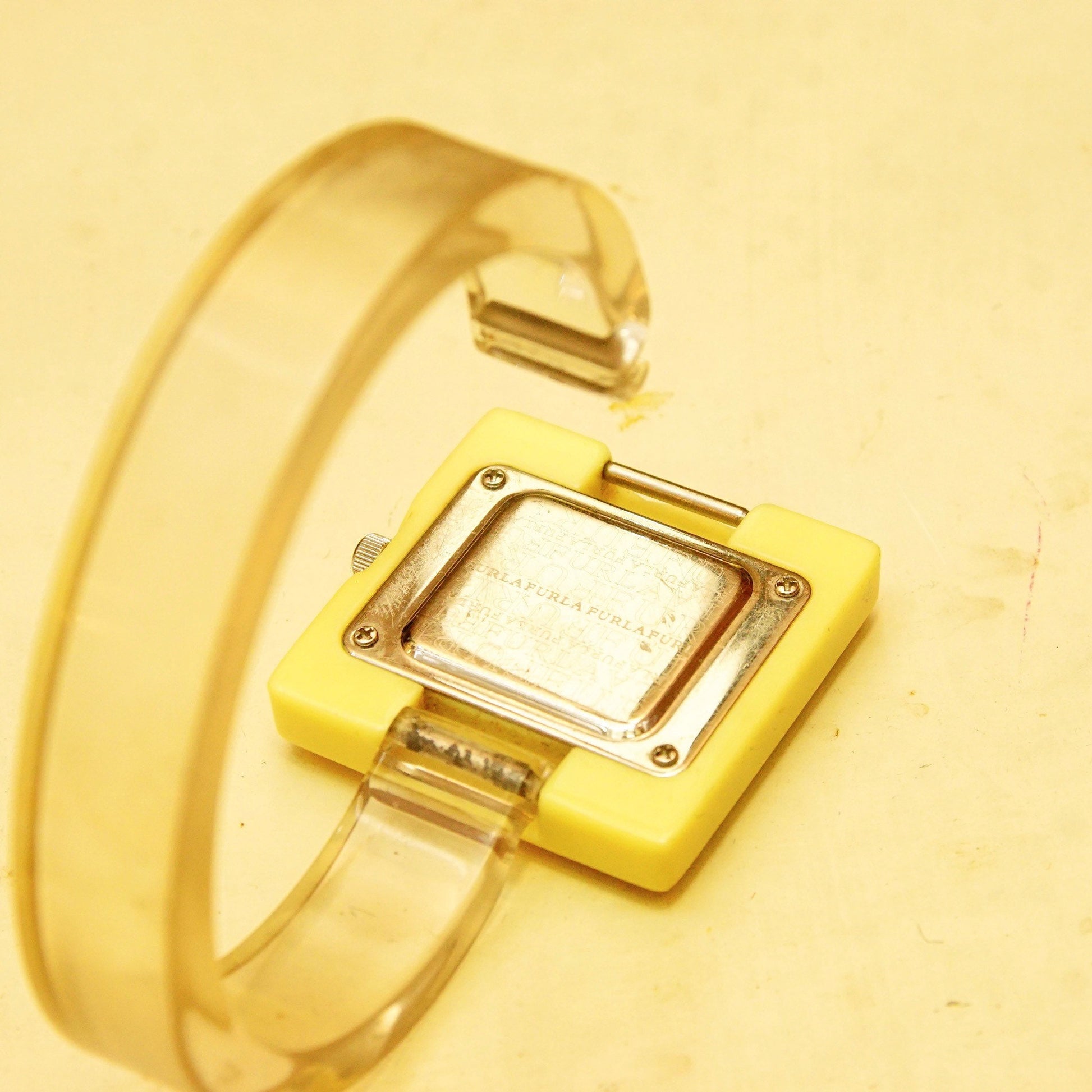 Vintage Furla cuff wristwatch with square beige plastic case, reflective dial, and manual movement, measuring 6 1/2 inches long, displaying a chunky retro mod style perfect for funky accessorizing.