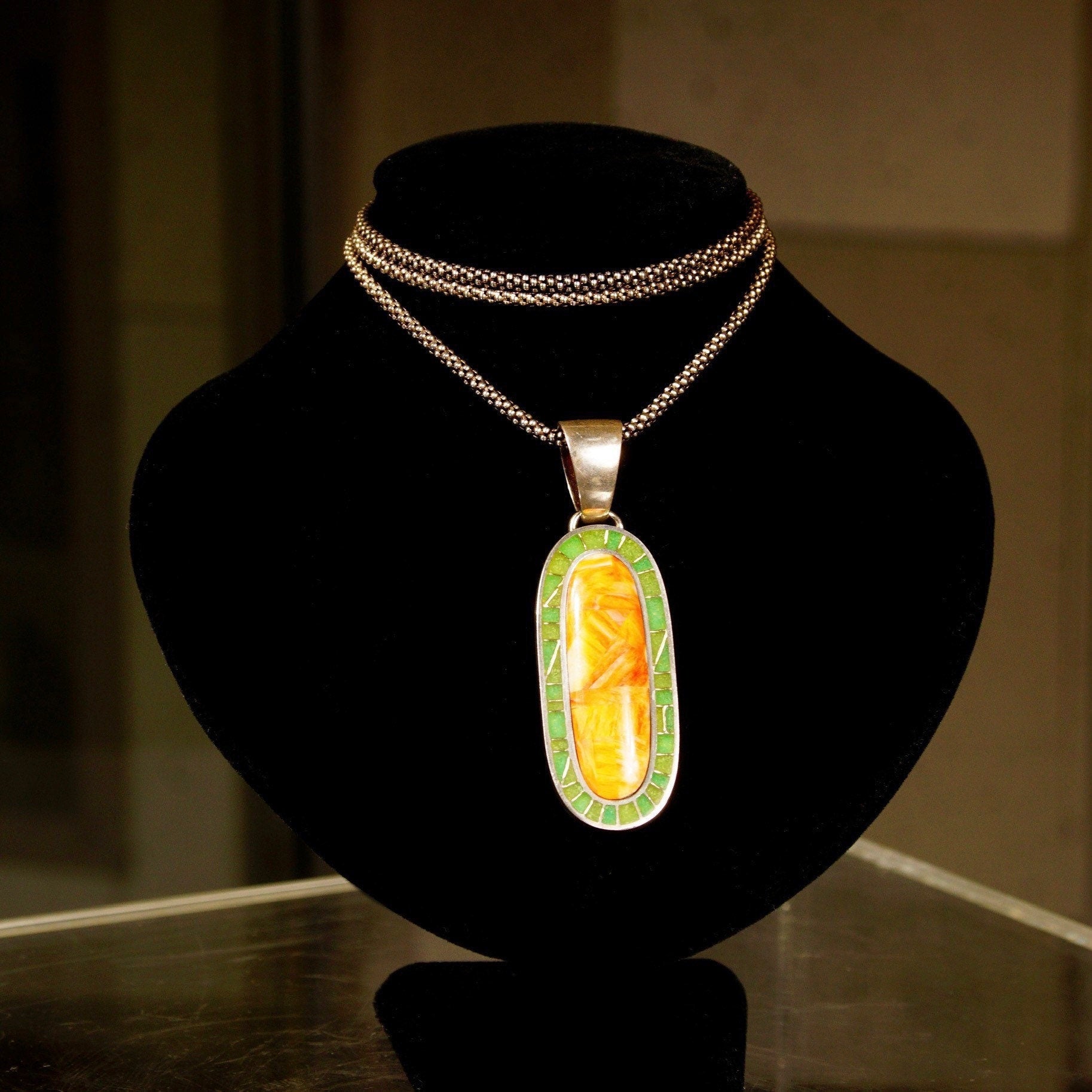 Vintage 925 sterling silver pendant necklace with orange carnelian agate and green aventurine mosaic inlay in a long oval shape, featuring a large silver bail, measuring 1 3/8 inches long.