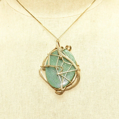 Vintage 10K gold plated wire wrapped green goldstone pendant necklace with abstract modernist bohemian design, measuring 2 5/8 inches long, featuring a large sparkly gemstone set in yellow gold.