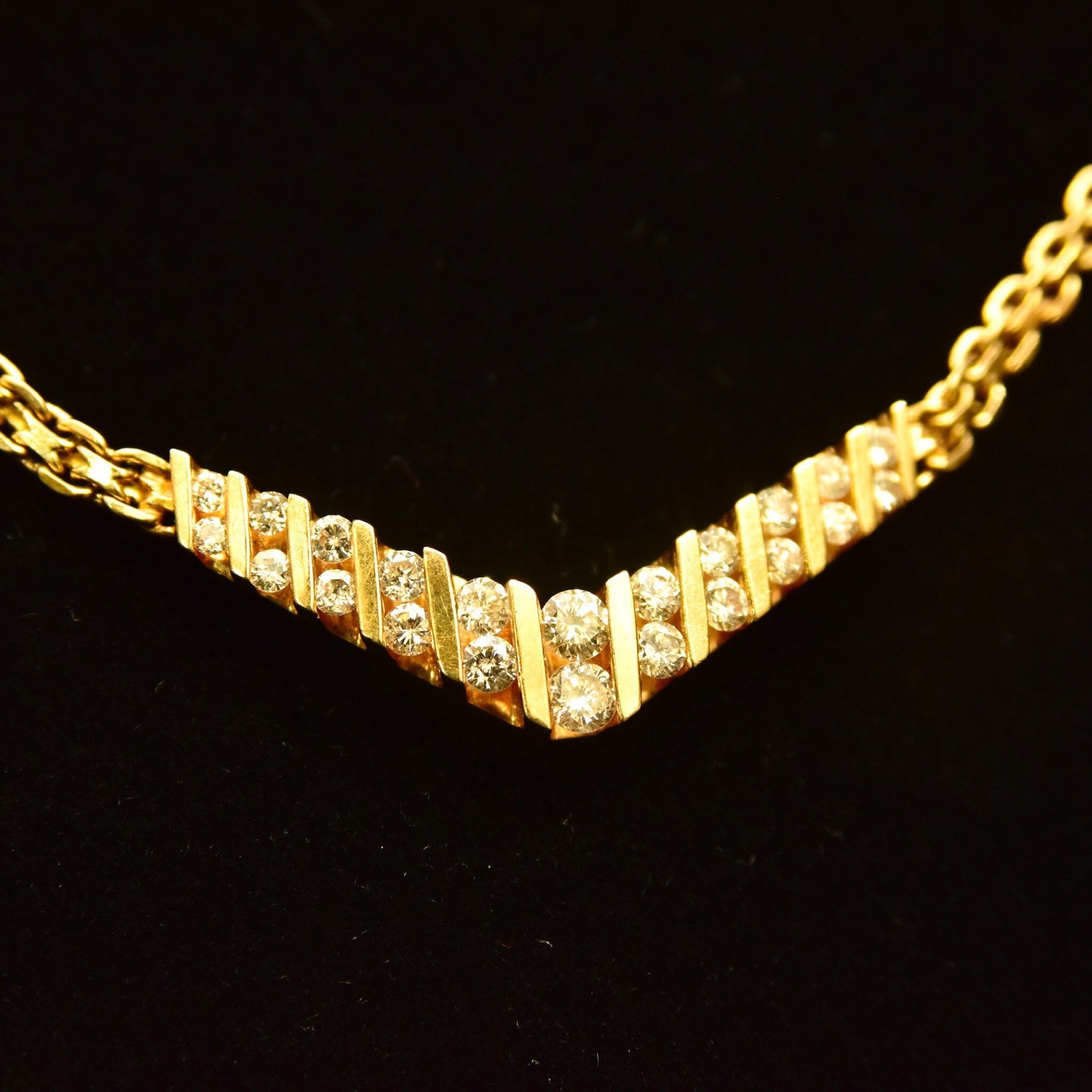 14K yellow gold diamond chevron necklace with brilliant round cut diamonds channel set in a V-shaped pendant on a delicate mesh link chain, 15 1/4 inches long.