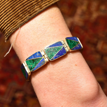 Vintage sterling silver link bracelet with geometric malachite and lapis lazuli inlay, measuring 7 1/4 inches long, displayed on a person's wrist against a brown textured background.