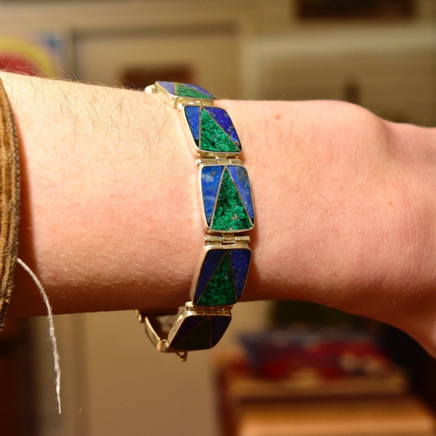 Sterling silver link bracelet with geometric inlays of malachite and lapis lazuli stones on a person's wrist, bohemian modernist style, 7 1/4 inches long.