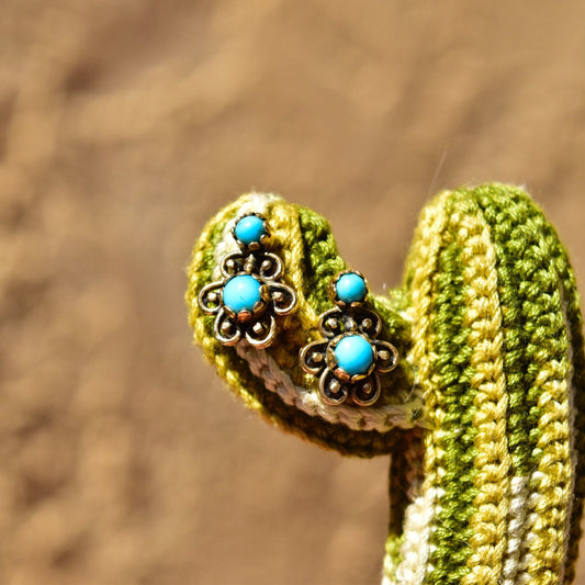 14K yellow gold crochet earrings with turquoise flower studs on a textured brown background