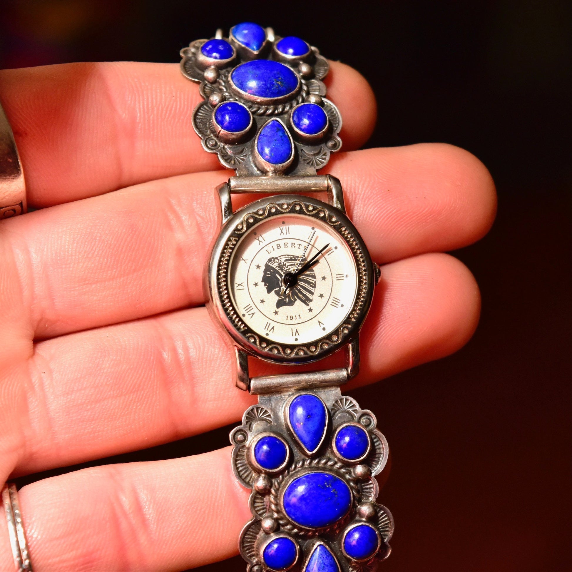 Vintage Navajo sterling silver ladies watch with blue lapis lazuli stones, featuring Liberty 1911 dial and adjustable bracelet band, crafted by A. Cadman. Legacy quartz automatic movement.