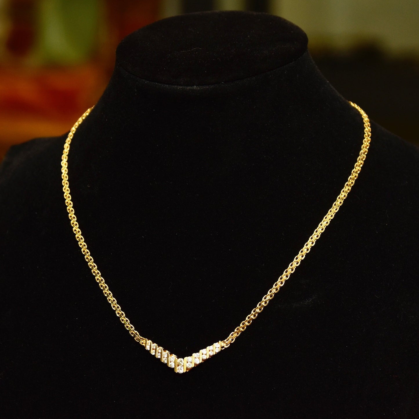 14K yellow gold diamond chevron necklace featuring a channel set brilliant diamond pendant on a delicate mesh link chain, measuring 15 1/4 inches in length, displayed on a black jewelry bust.