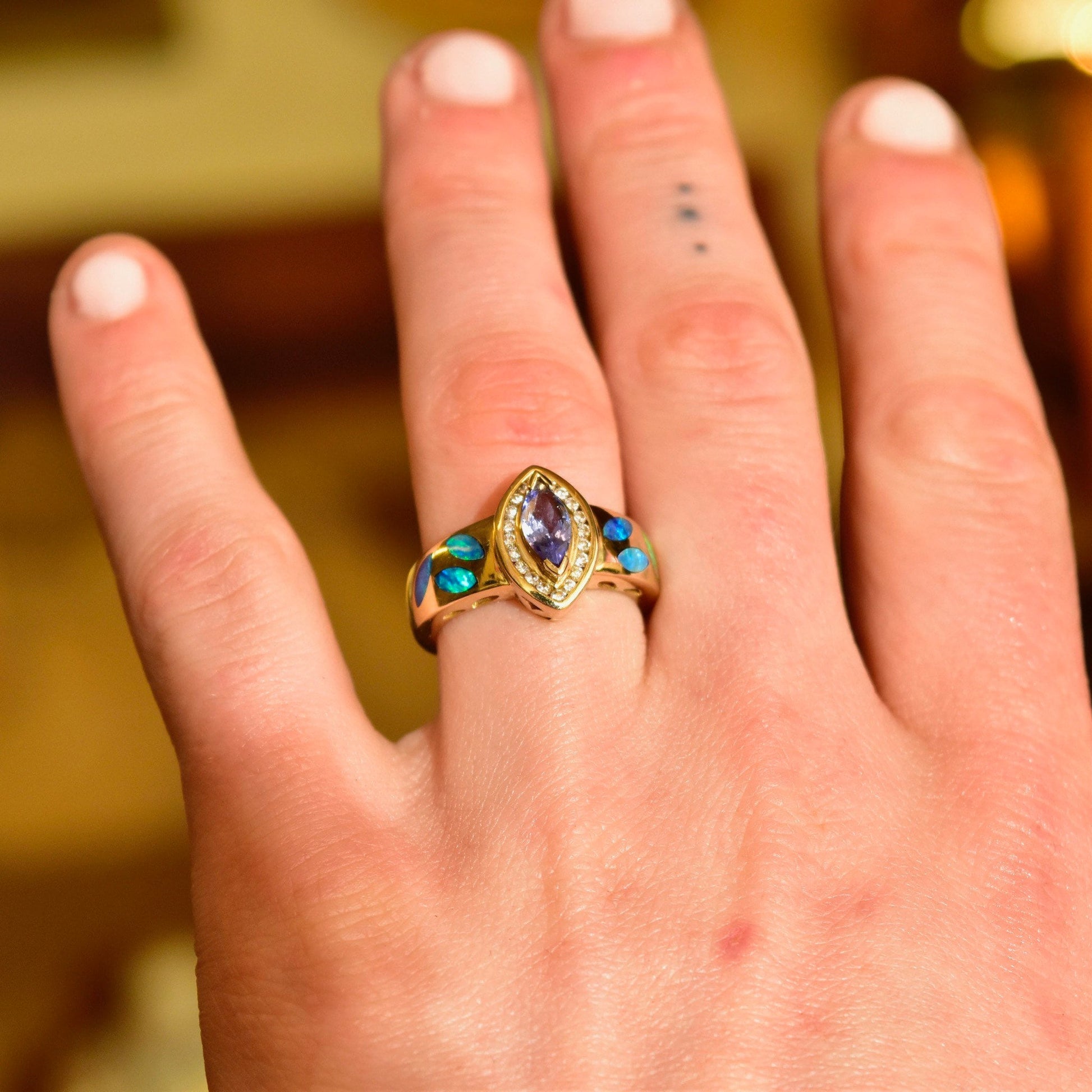 14K gold marquise-cut tanzanite ring with diamond halo and blue opal inlay on hand, size 7 1/2 US.
