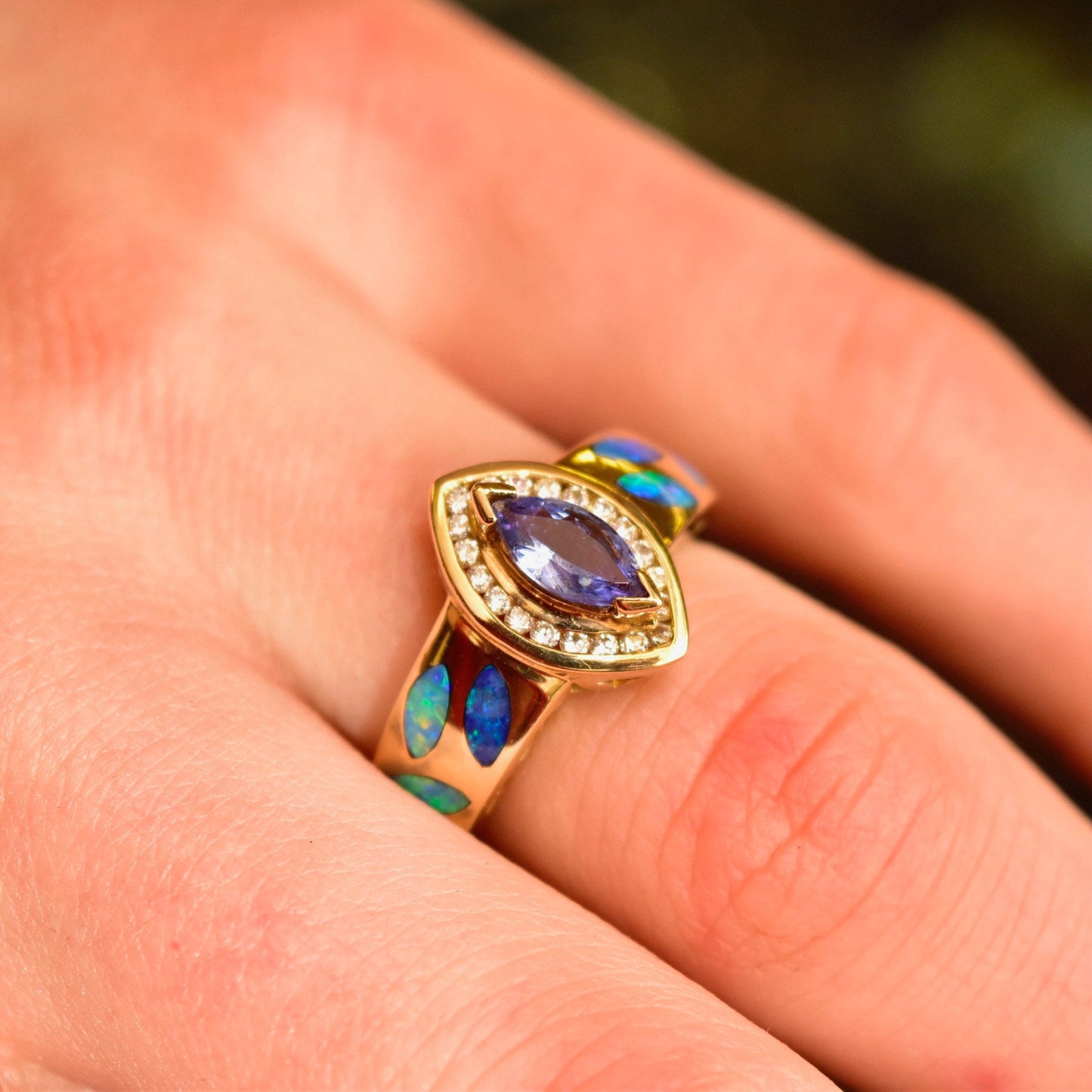 14K yellow gold marquise tanzanite ring with diamond halo and colorful blue opal inlay on finger, size 7 1/2 US cocktail ring