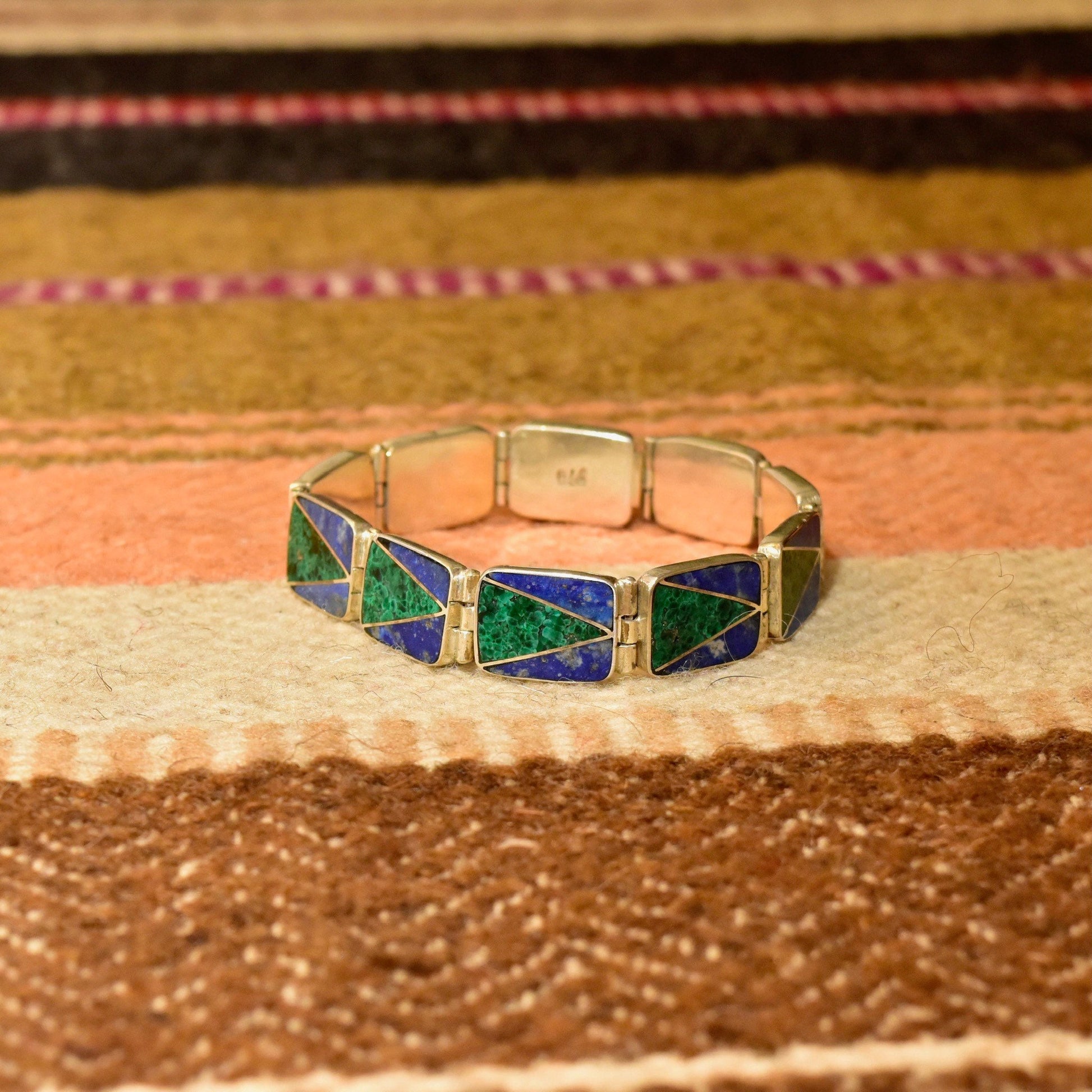 Vintage sterling silver link bracelet with geometric malachite and lapis lazuli inlay on a colorful woven textile background, bohemian modernist style, 7 1/4 inches long