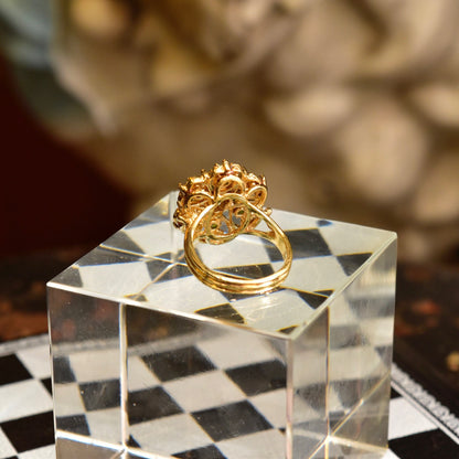 14K yellow gold emerald and diamond cluster dome cocktail ring on geometric patterned surface
