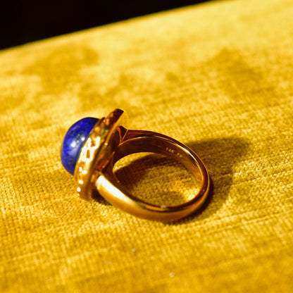 14K yellow gold cocktail ring with cobalt blue lapis lazuli cabochon gemstone solitaire, hollow construction, size 7 1/2 US, on textured gold fabric background
