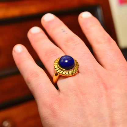 14K yellow gold hollow cocktail ring featuring a cobalt blue lapis lazuli cabochon gemstone solitaire, shown on a hand, size 7 1/2 US.