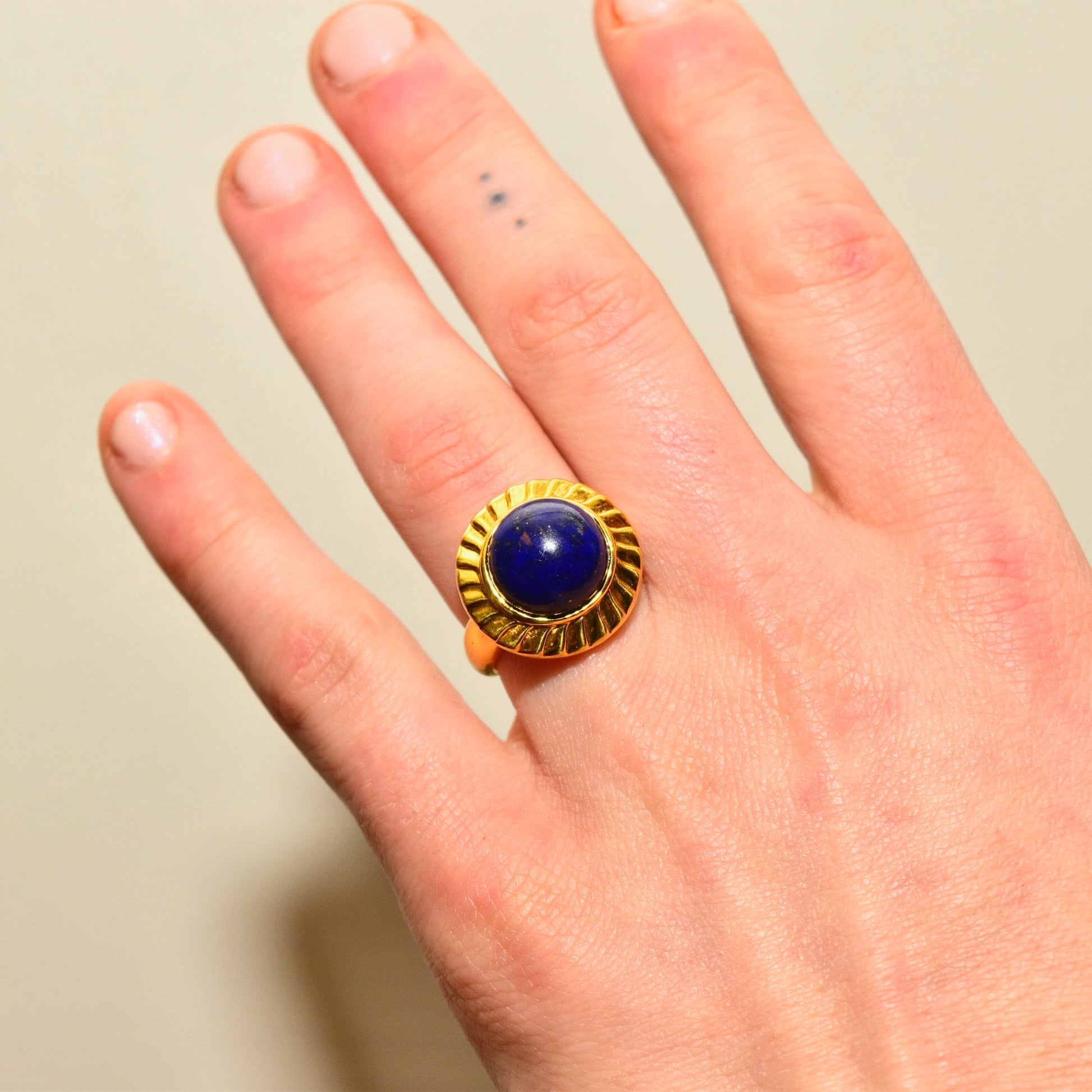 14K yellow gold lapis lazuli cabochon cocktail ring on hand, featuring a round cobalt blue gemstone solitaire, size 7 1/2 US.