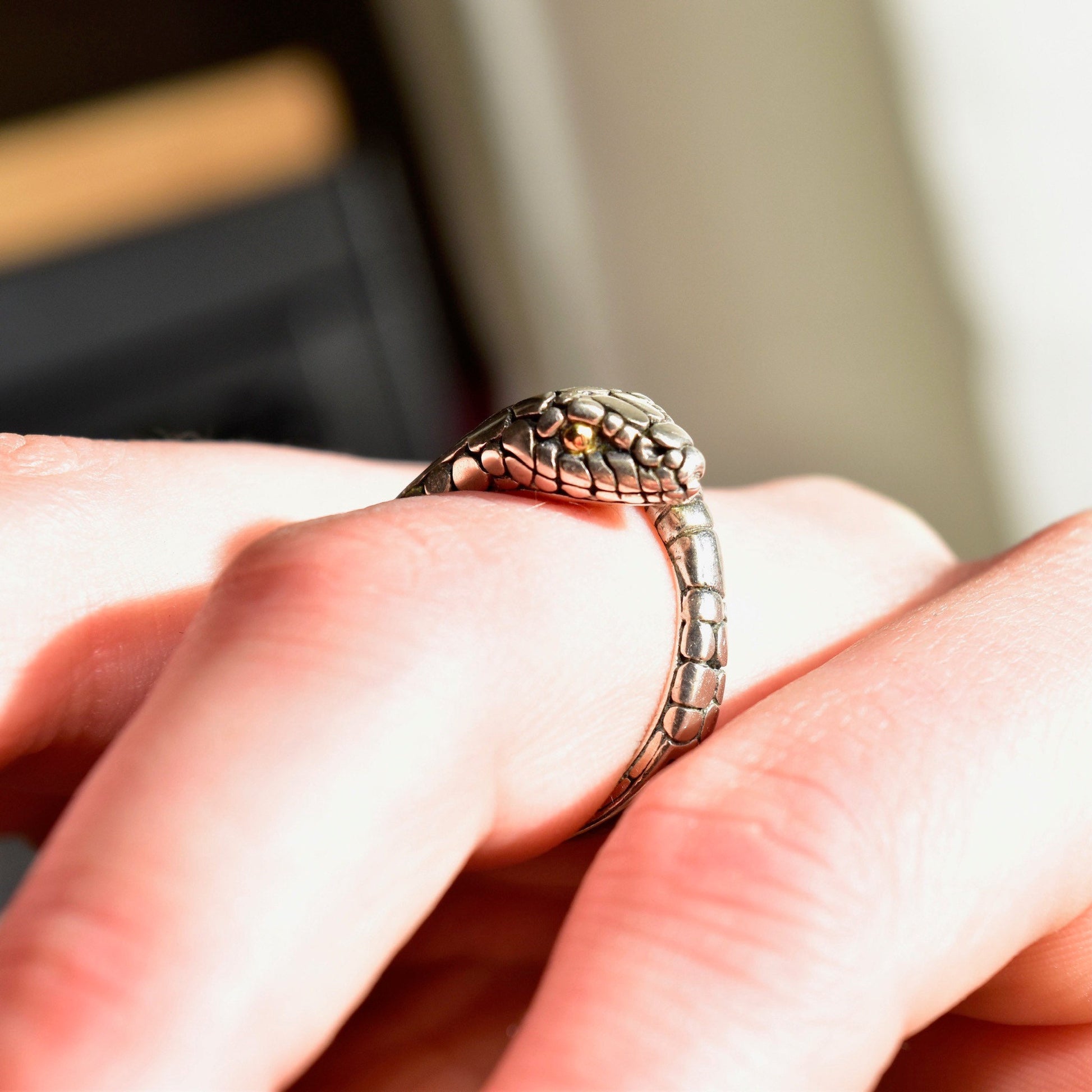 Vintage sterling silver snake ring with 18K gold accents and iridescent abalone shell inlay, coiled design resembling a rattlesnake, worn on a finger