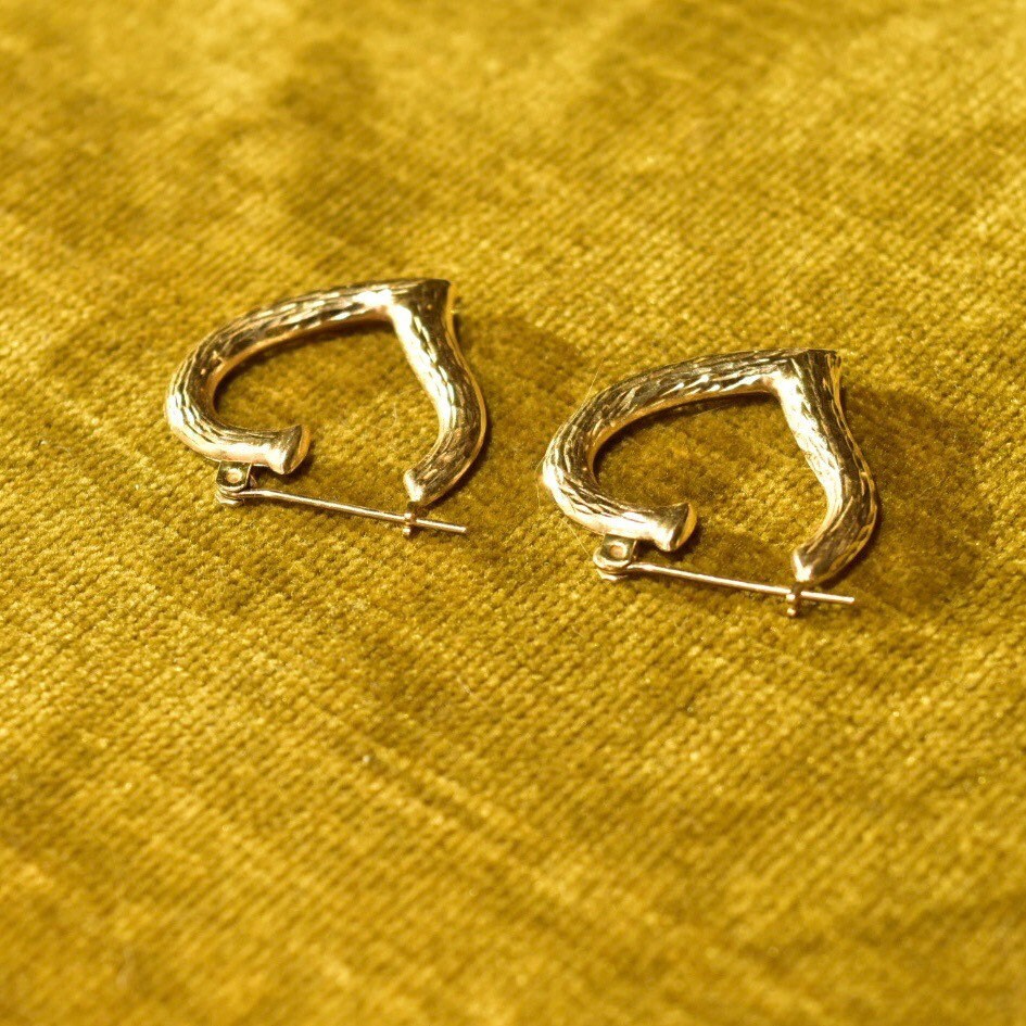 Vintage 14K gold hammered heart hoop earrings on textured yellow gold fabric