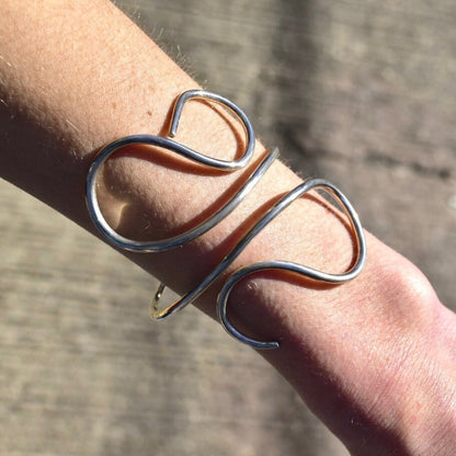 Vintage sterling silver wire wrap cuff bracelet on wrist, minimalist solid silver swirl design, adjustable bohemian 925 silver jewelry.