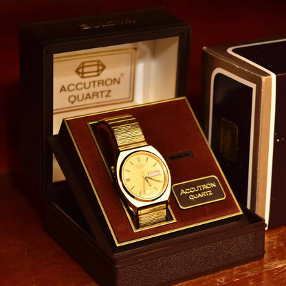 Vintage 1988 Bulova Accutron gold tone Swiss quartz day/date wristwatch in original box with papers, featuring a Speidel two-tone stretch band and measuring 7 inches.