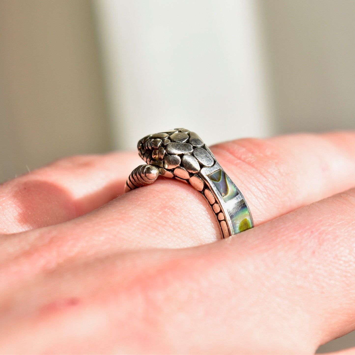 Vintage sterling silver snake ring with abalone inlay and 18K gold accents, featuring an engraved rattlesnake design that coils around the finger. The snake's eye is gold and the iridescent abalone shell creates a striking contrast against the silver. Ring size is 7 1/2 US.